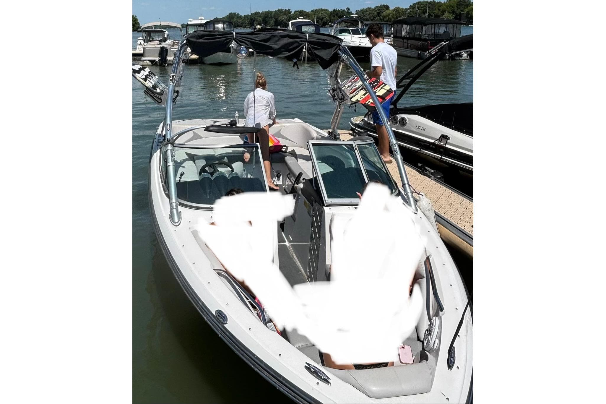2008 MasterCraft X-15 boat docked with people onboard, featuring wakeboards and a sunny day.