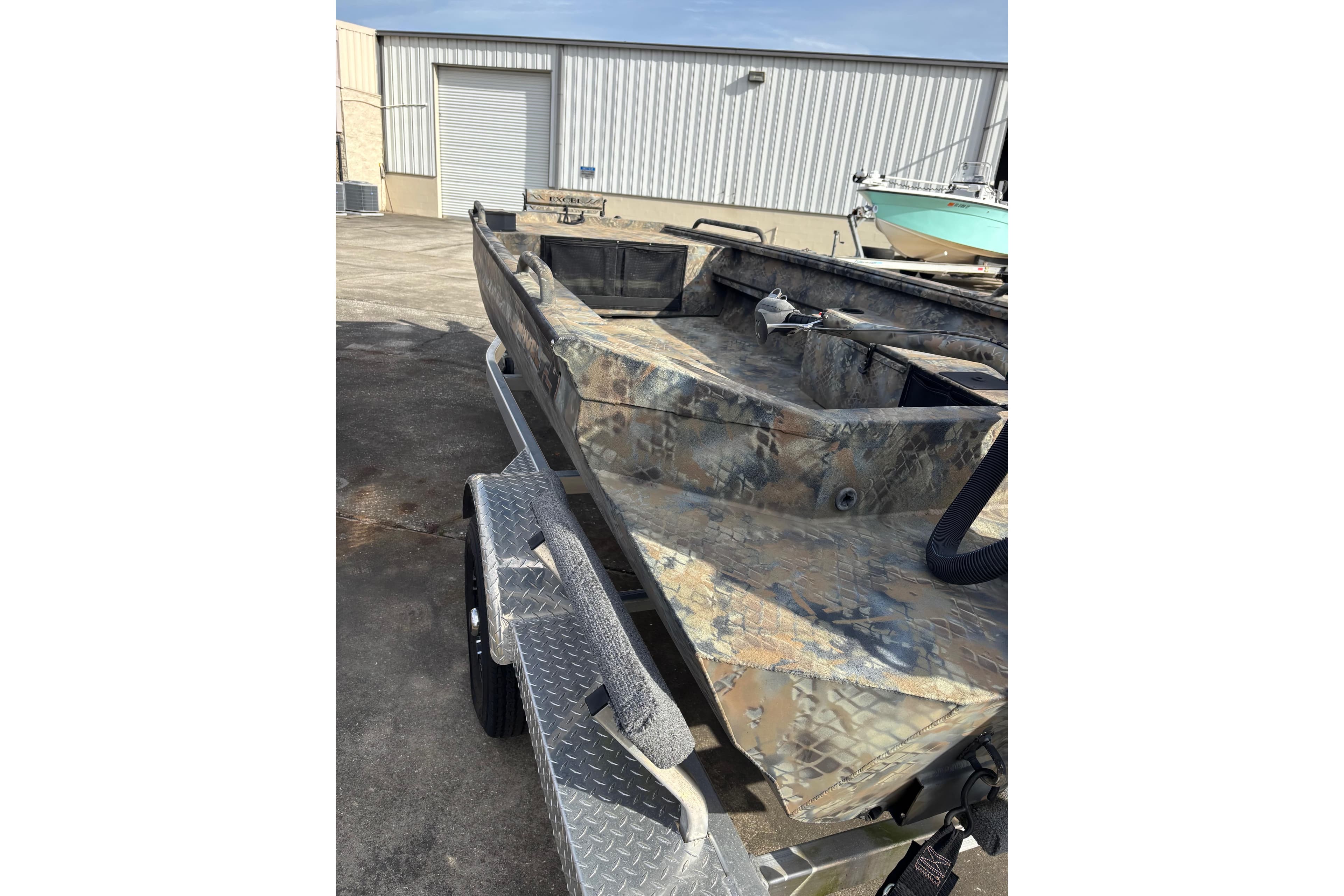 2023 Excel 1754 Shallow Water F4 boat on trailer, camo design, outdoor setting.
