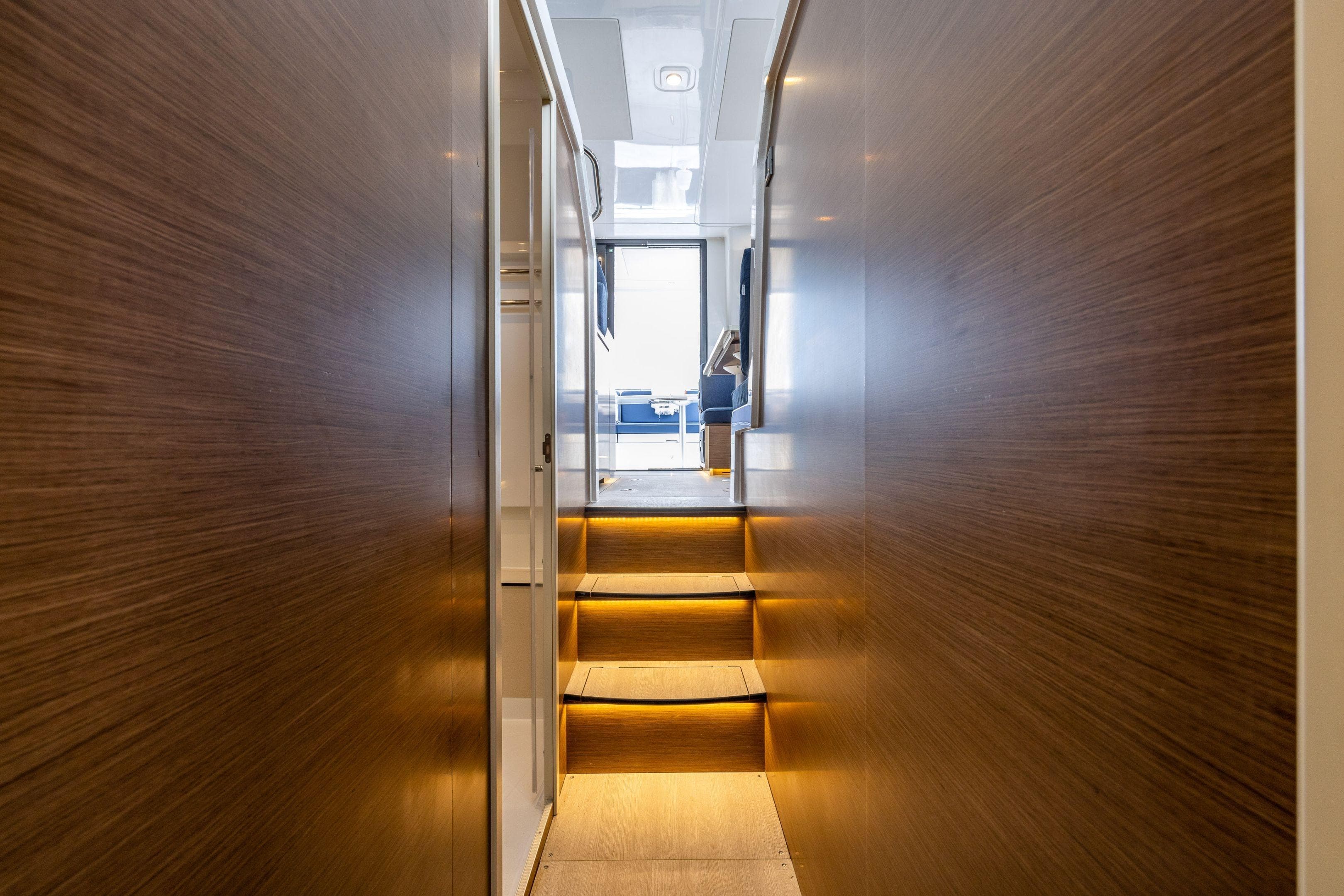 Interior view of 2026 Delphia D11 Flybridge yacht with wooden walls and illuminated stairs.