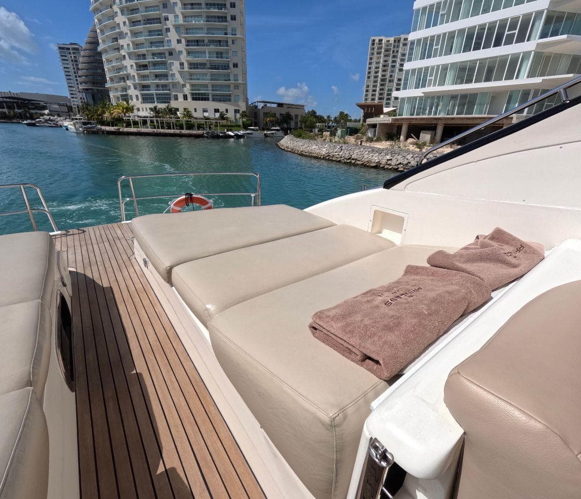 Luxurious 2004 Princess 65 yacht deck with sun loungers, overlooking marina and modern buildings.