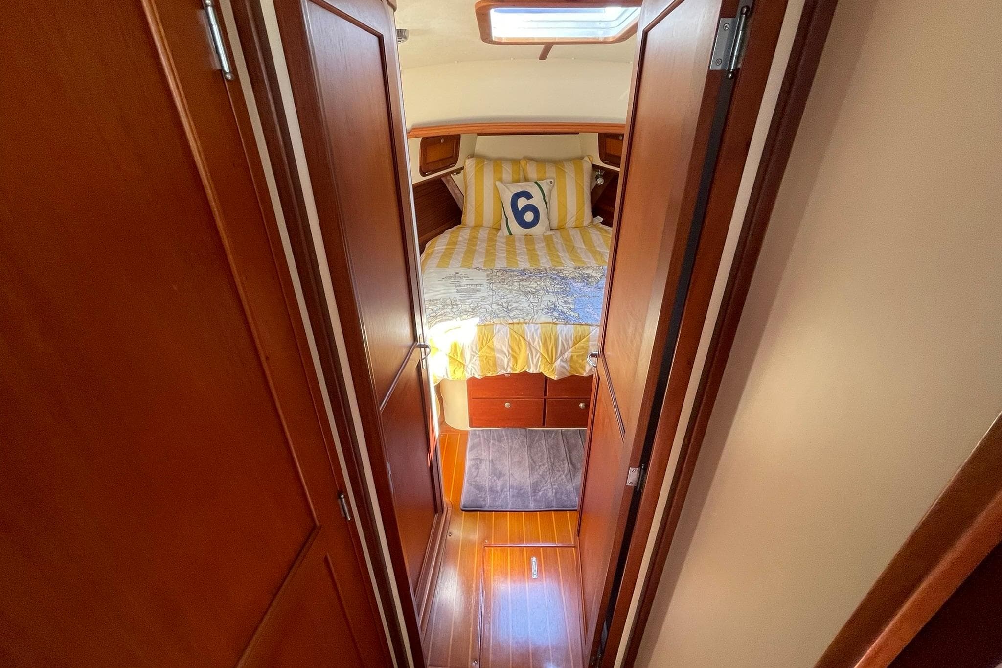 Cozy cabin interior of 1999 Legacy Yachts 40 Sedan with striped bedding and wooden finish.