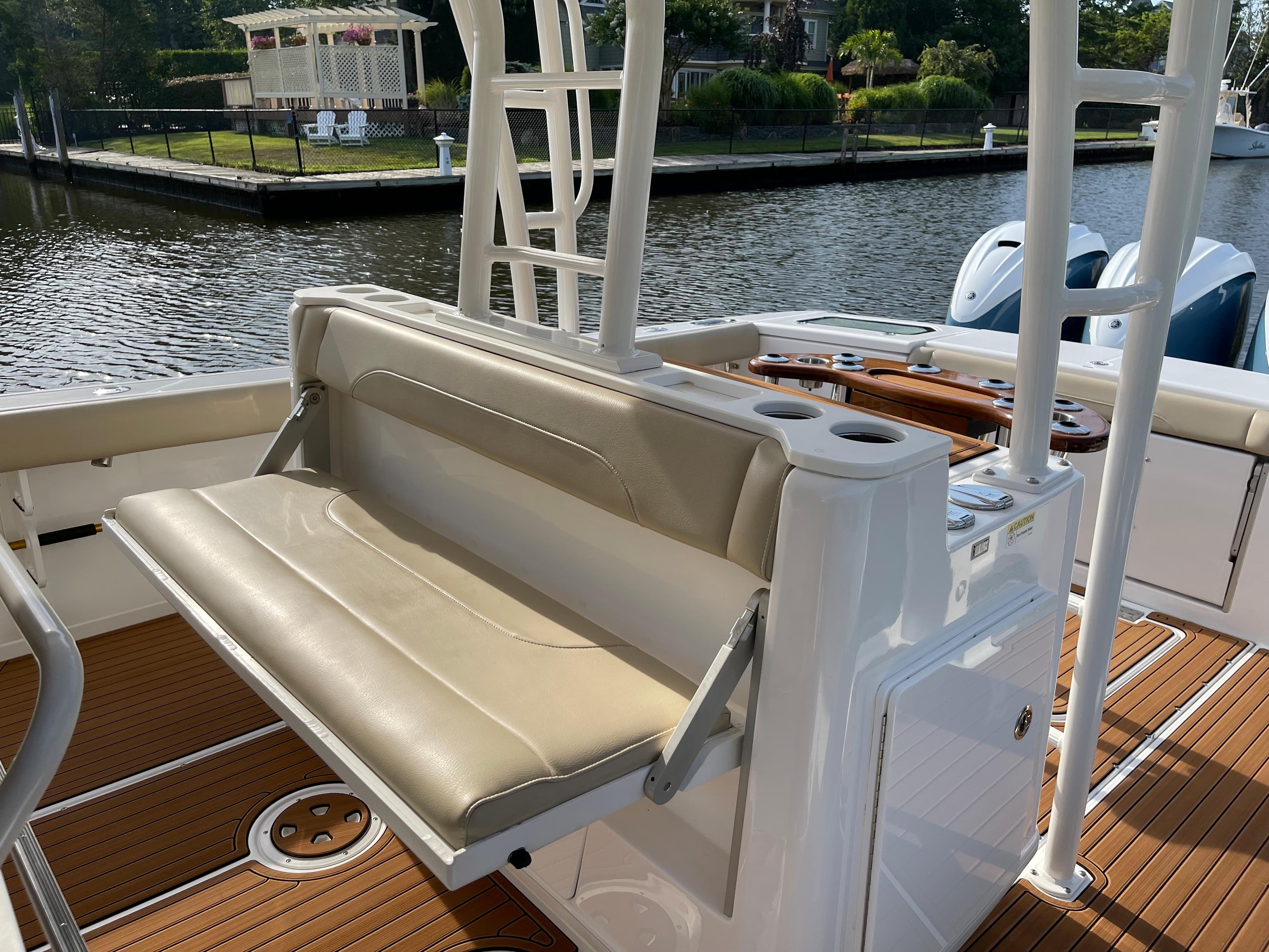 2019 Everglades 435 CC boat interior with beige seating and wooden deck by the water.
