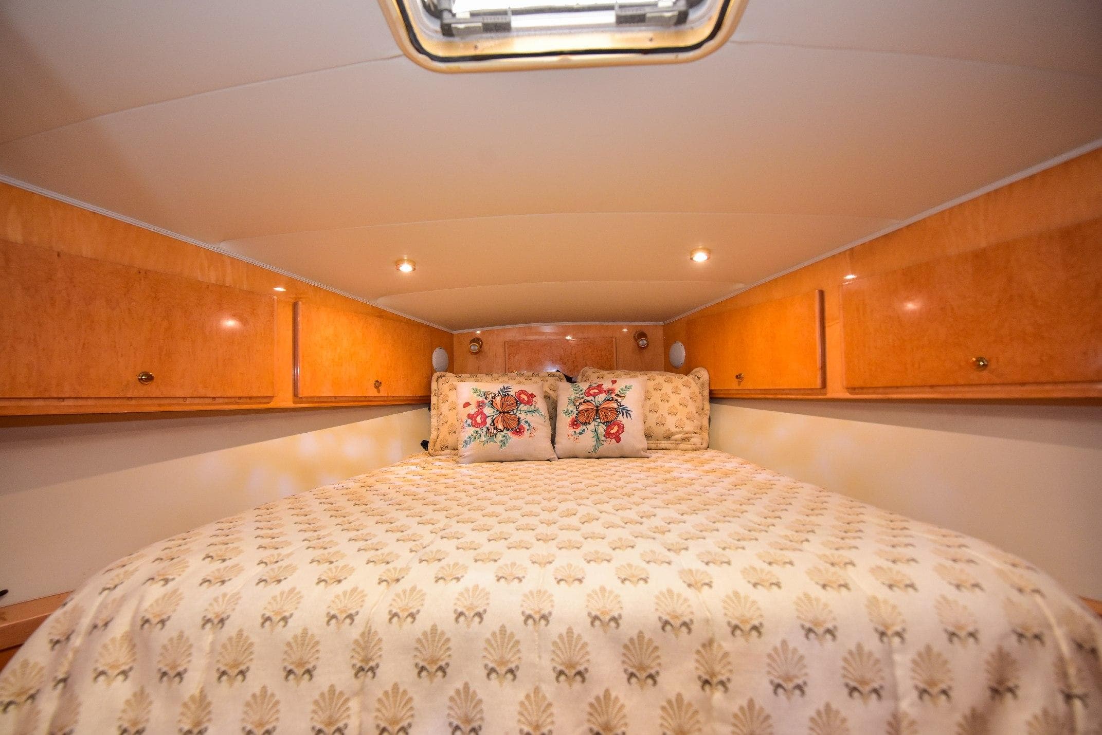 Cozy bedroom in 2004 Navigator Rival yacht with wood cabinets and floral bedding.