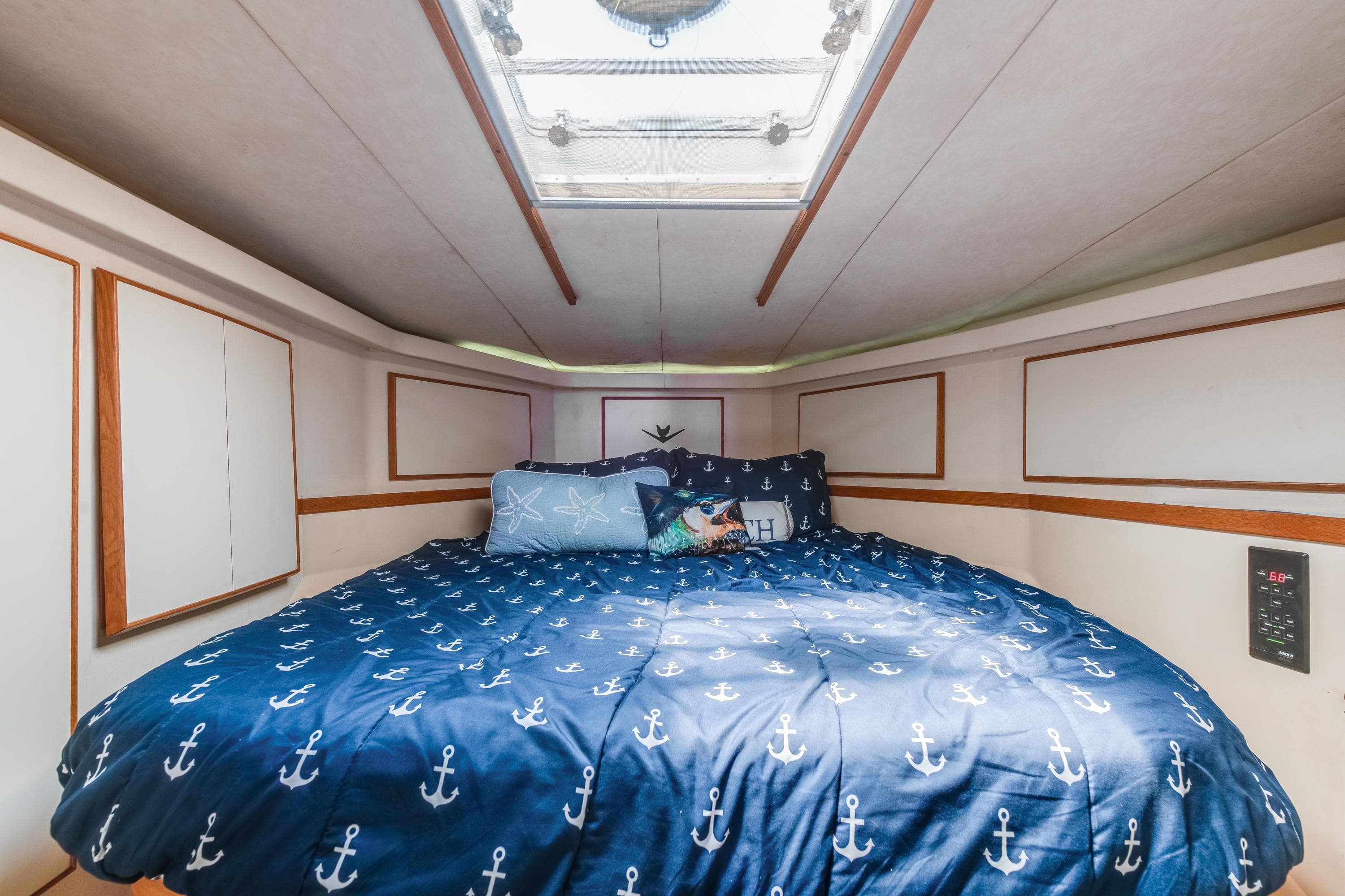 Cozy bedroom in 1990 Bertram 50 Convertible yacht with nautical-themed bedding.