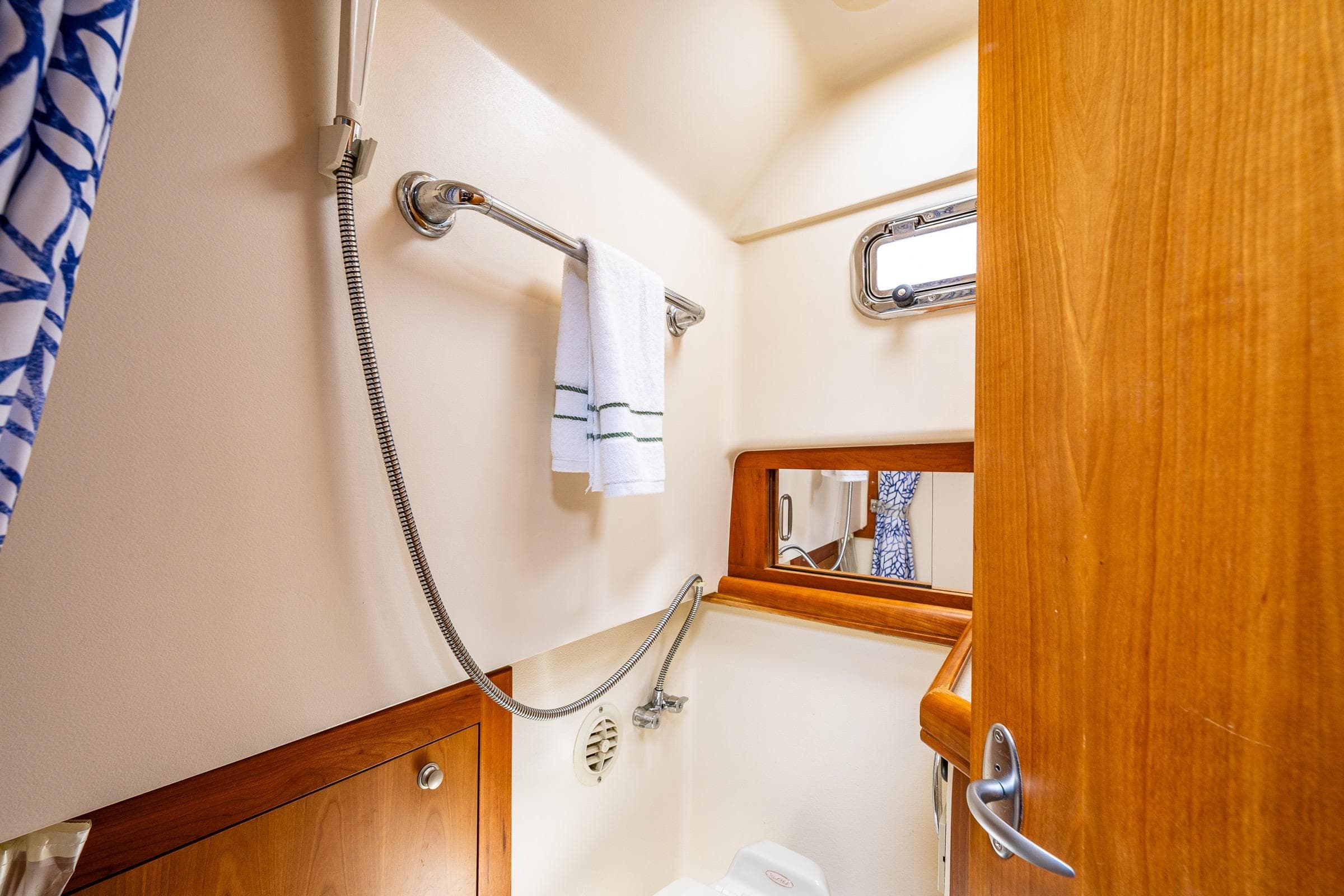 2004 Mainship Pilot 34 bathroom with shower, towel rack and wooden cabinetry.