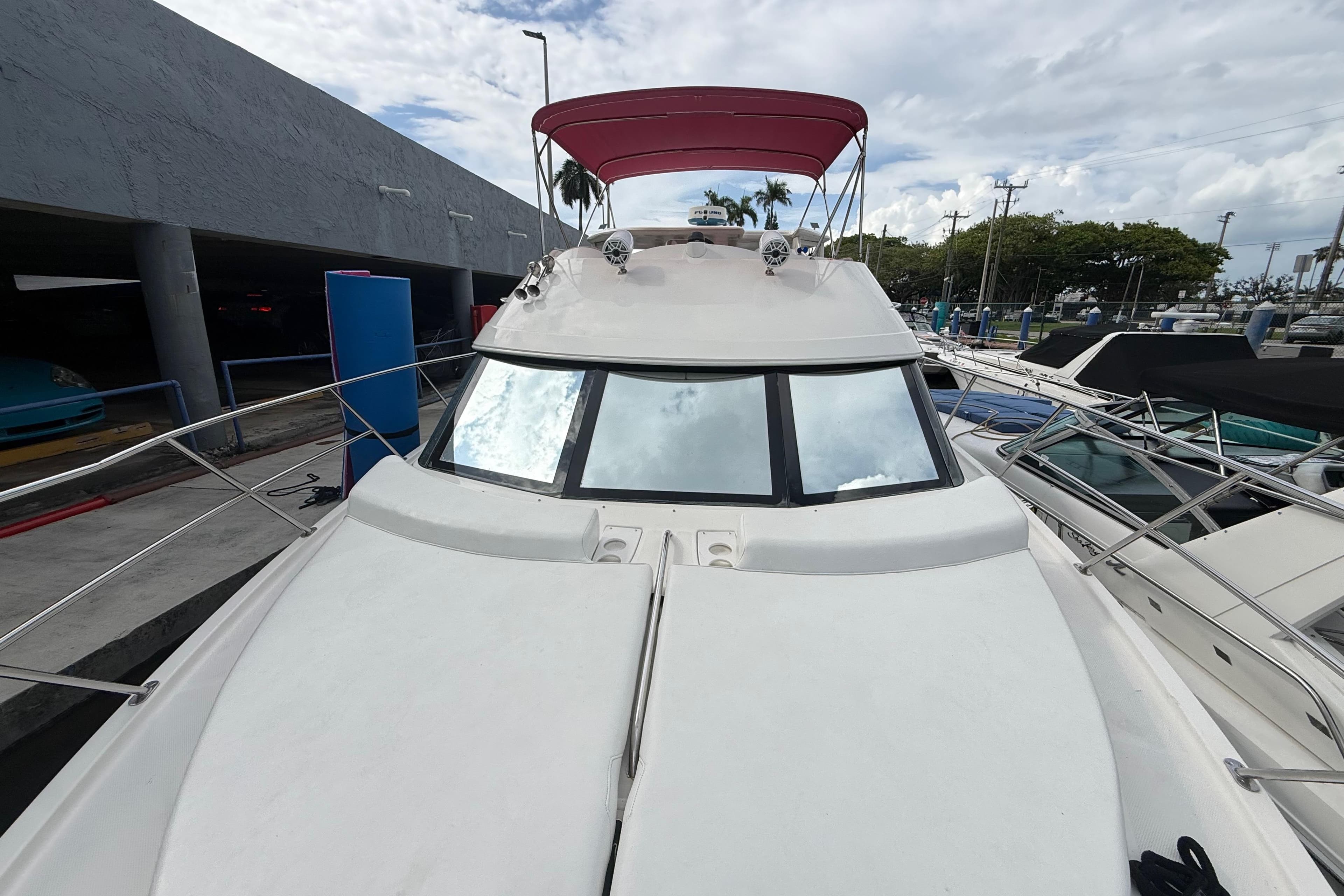 2007 Meridian 459 Motoryacht with red canopy, docked at marina under cloudy sky.