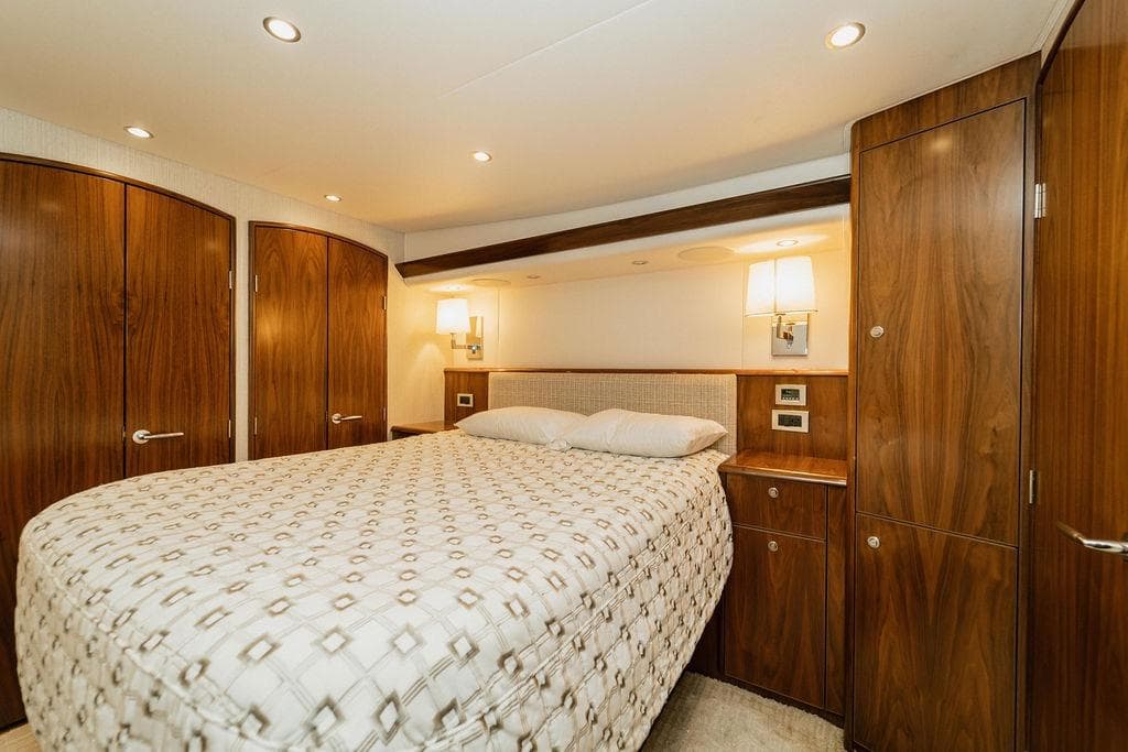 Luxurious bedroom interior of 2021 Viking 58 Convertible yacht with elegant wood finish.