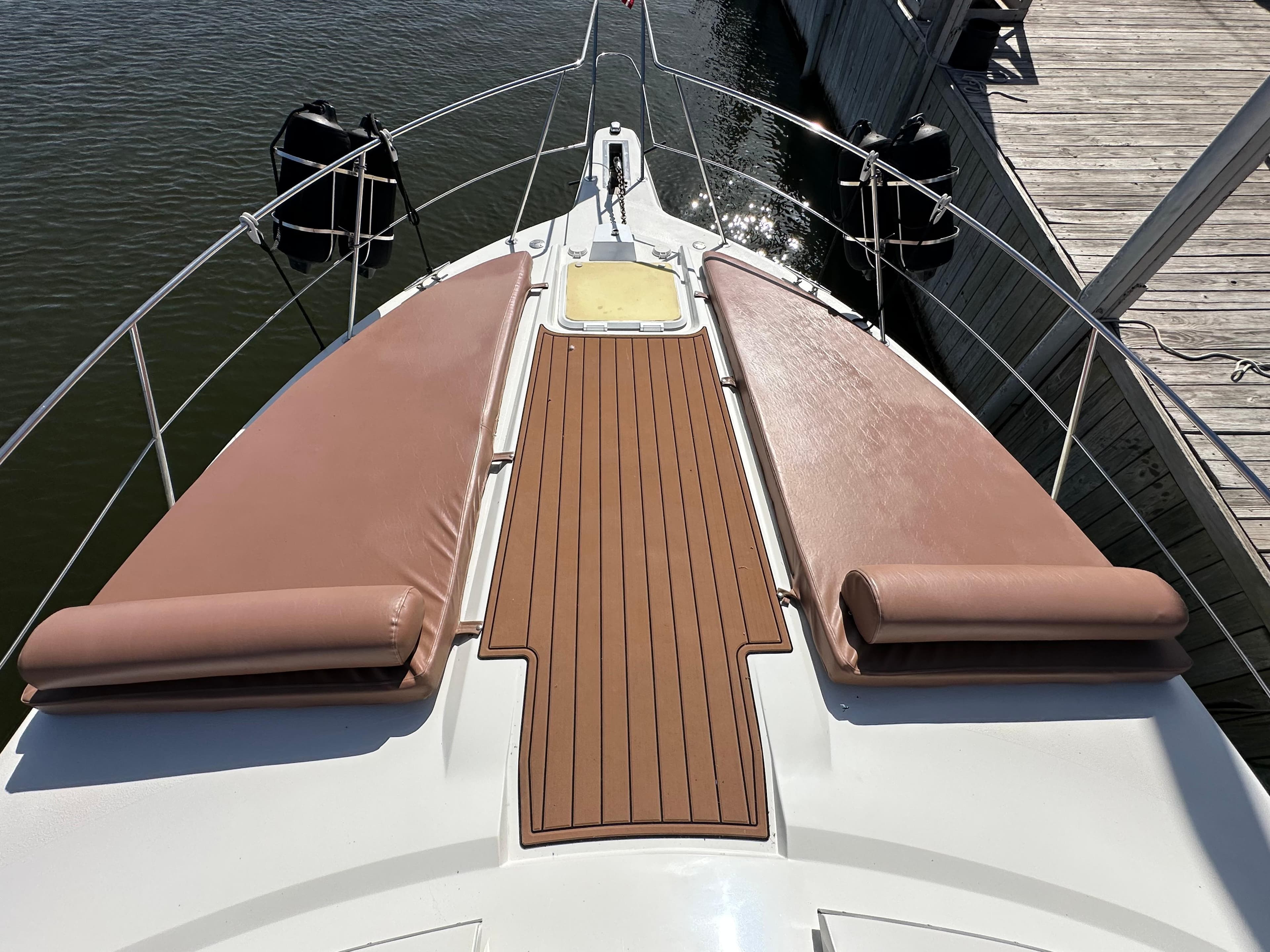1996 Carver 38 Santego yacht bow with cushioned sun pads and wooden deck.