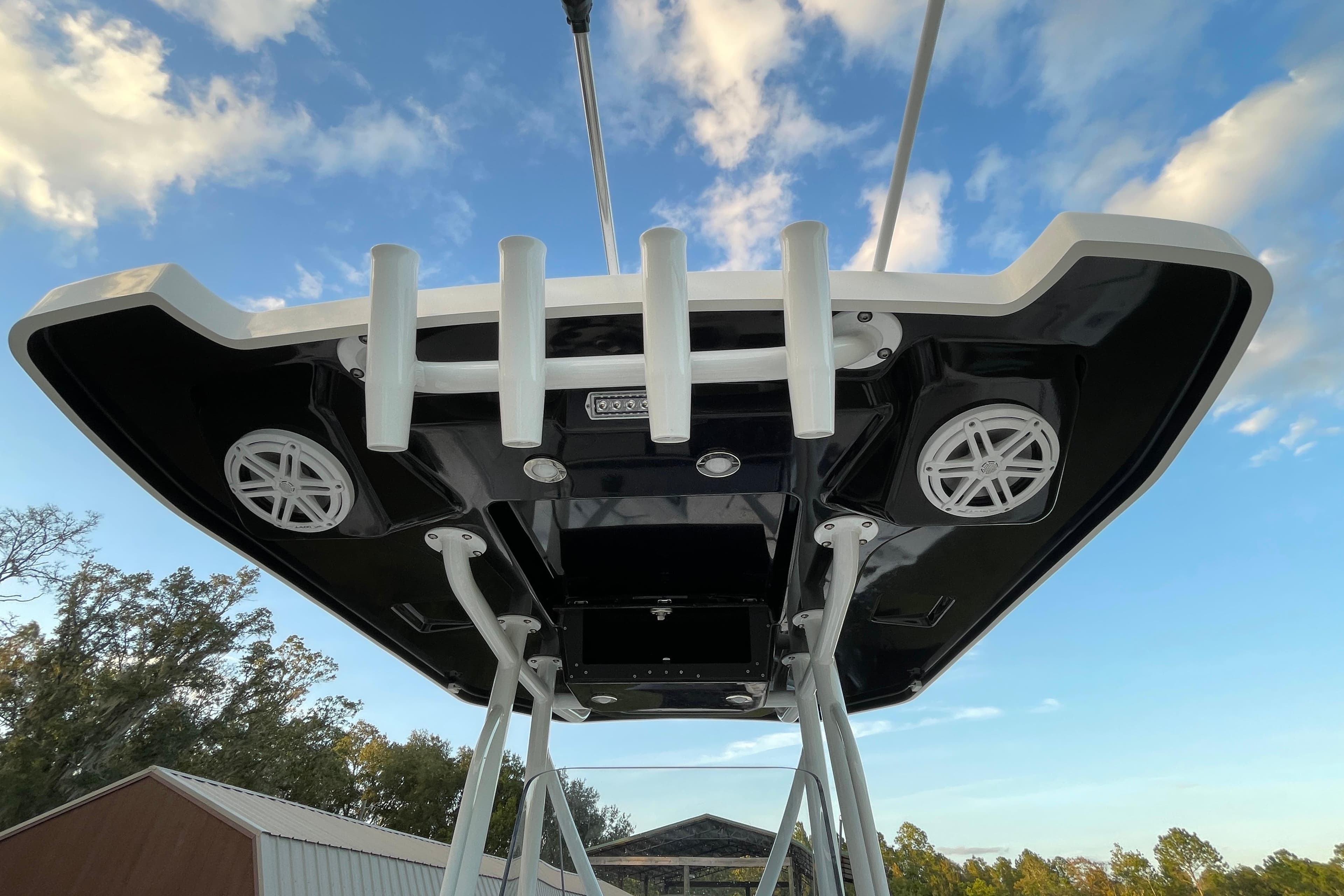 2022 Blackfin 252 CC boat roof with rod holders and speakers against blue sky.
