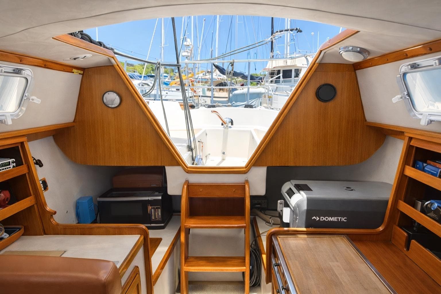 Interior of a 1979 Lancer Sloop sailboat with wooden cabinetry and marina view.