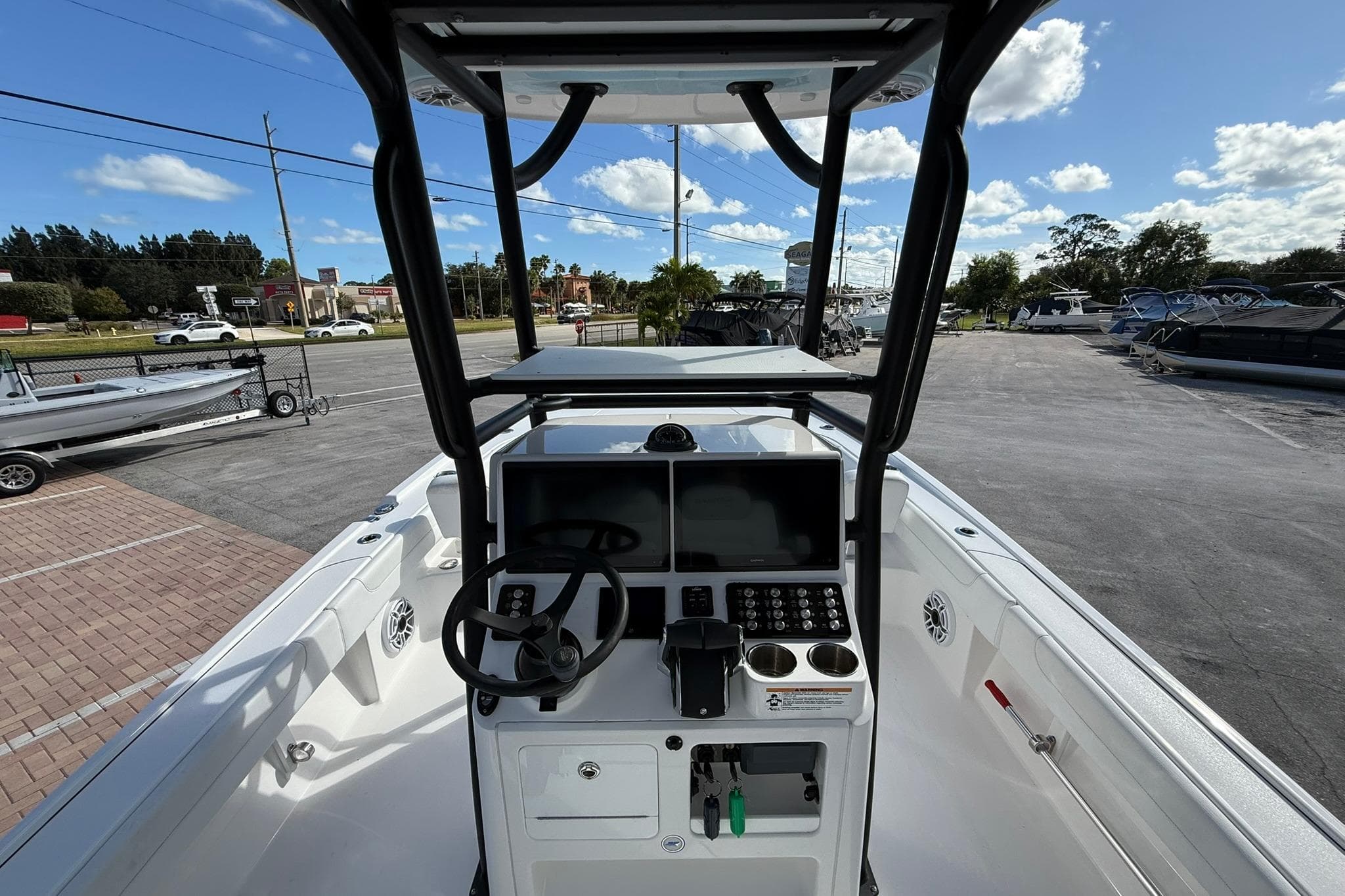 2023 Caymas 28 HB Twin boat dashboard with steering wheel and controls, parked outdoors.