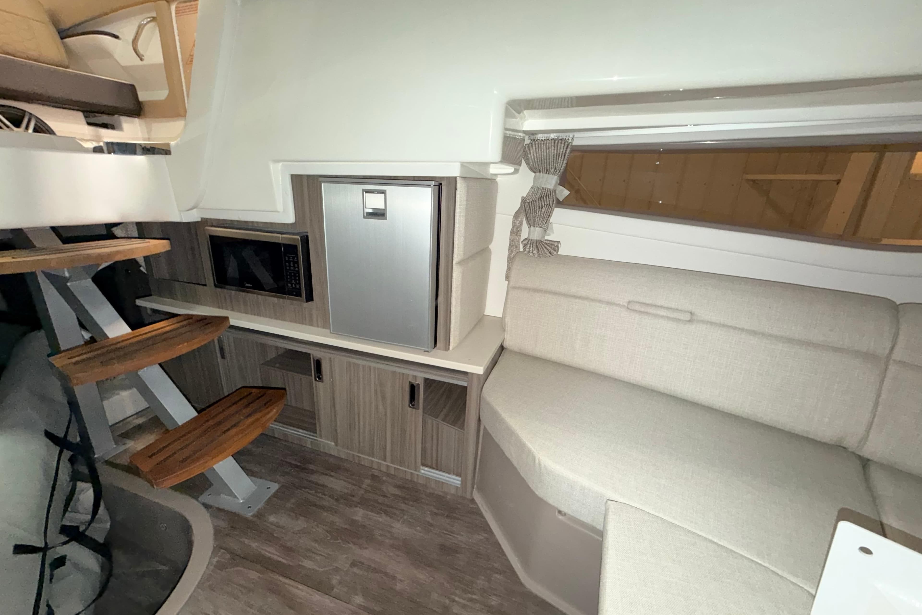 Interior of 2026 Sea Ray Sundancer 320 Coupe with modern seating and kitchenette.