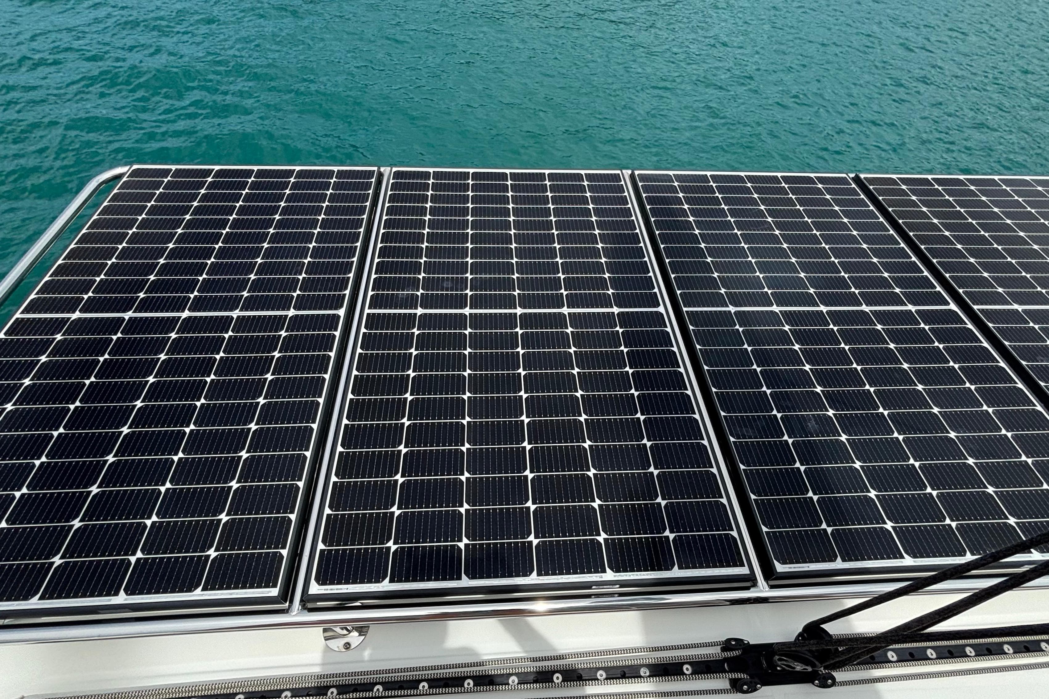 Solar panels on a 2023 Lagoon 46 catamaran, floating on turquoise water.