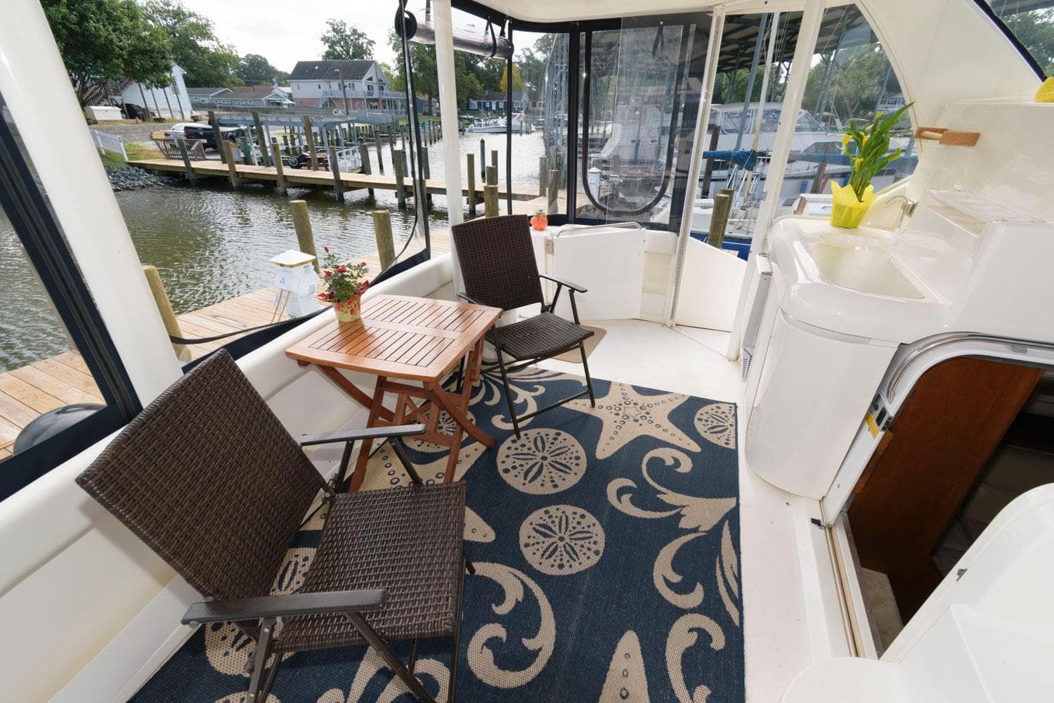 1999 Cruisers Yachts 3750 Motoryacht deck with chairs, table, and nautical-themed rug.