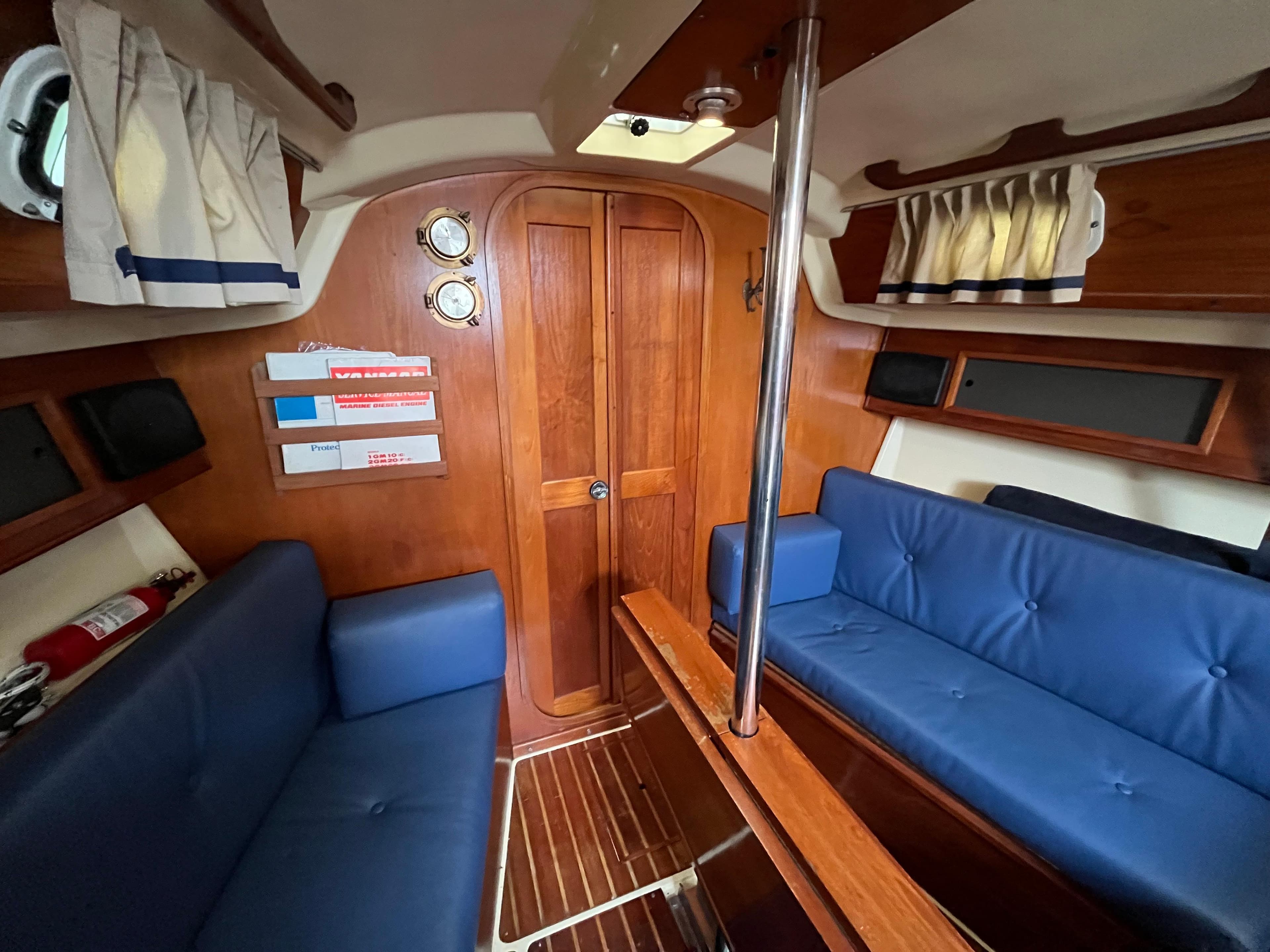 Interior of a 1986 Pearson 33-2 sailboat with blue seating and wooden finishes.