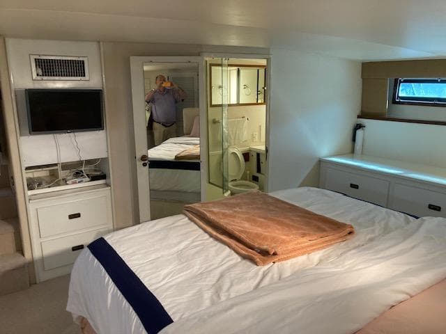 1977 Bertram 58 Motor Yacht bedroom with TV, mirror, and ensuite bathroom.