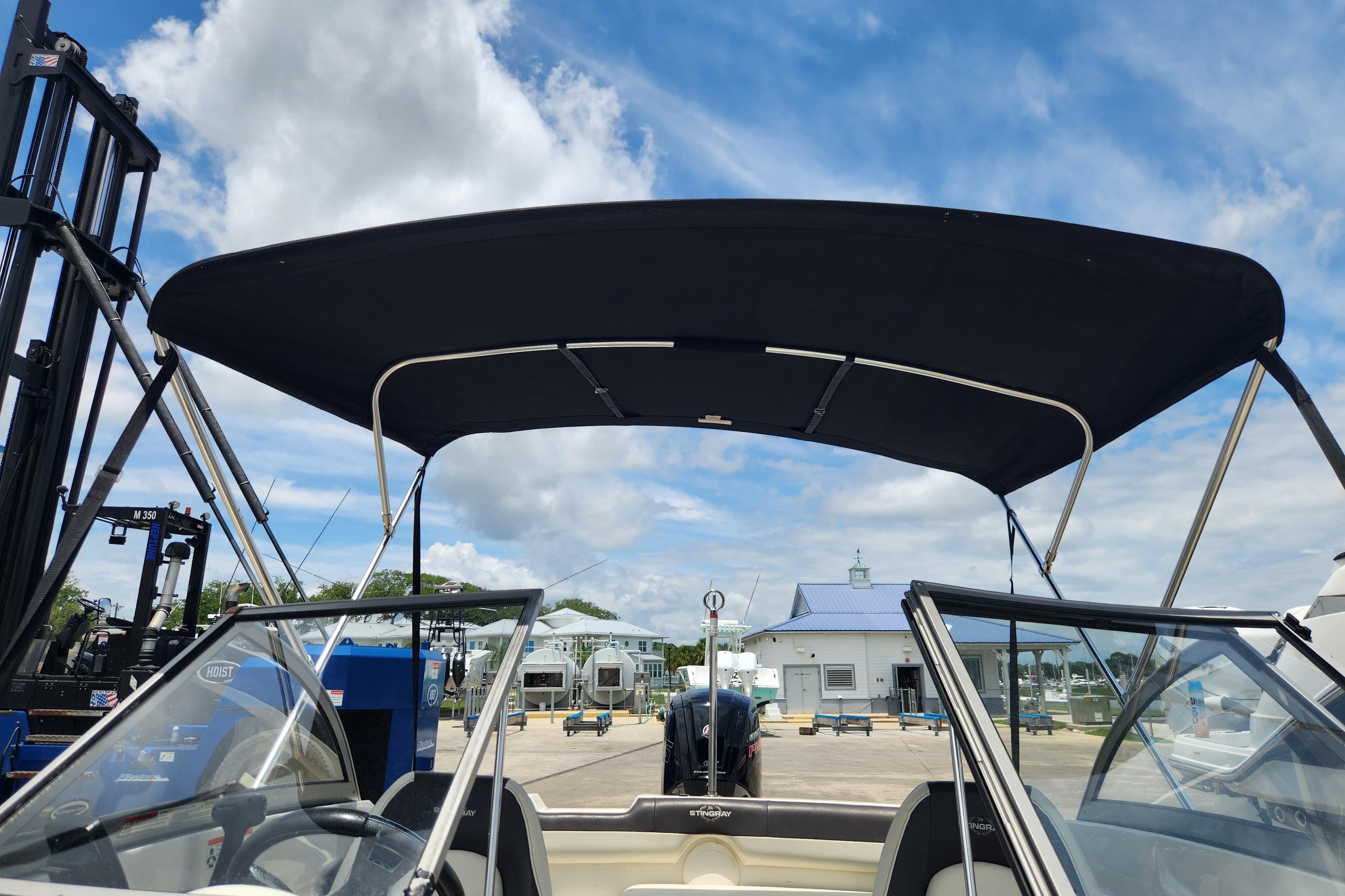 2018 Stingray 191 DC boat with bimini top, docked under a blue sky.