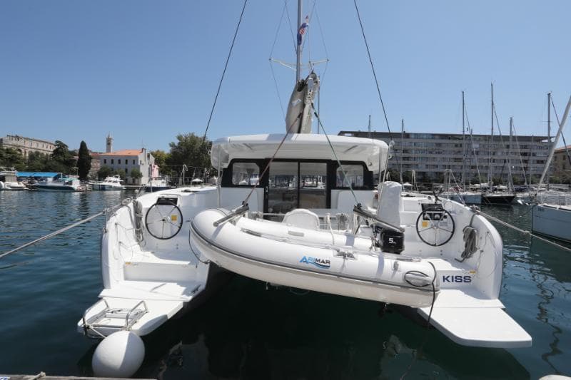 Excess 11 catamaran, 2023 model, docked with inflatable boat, marina background.