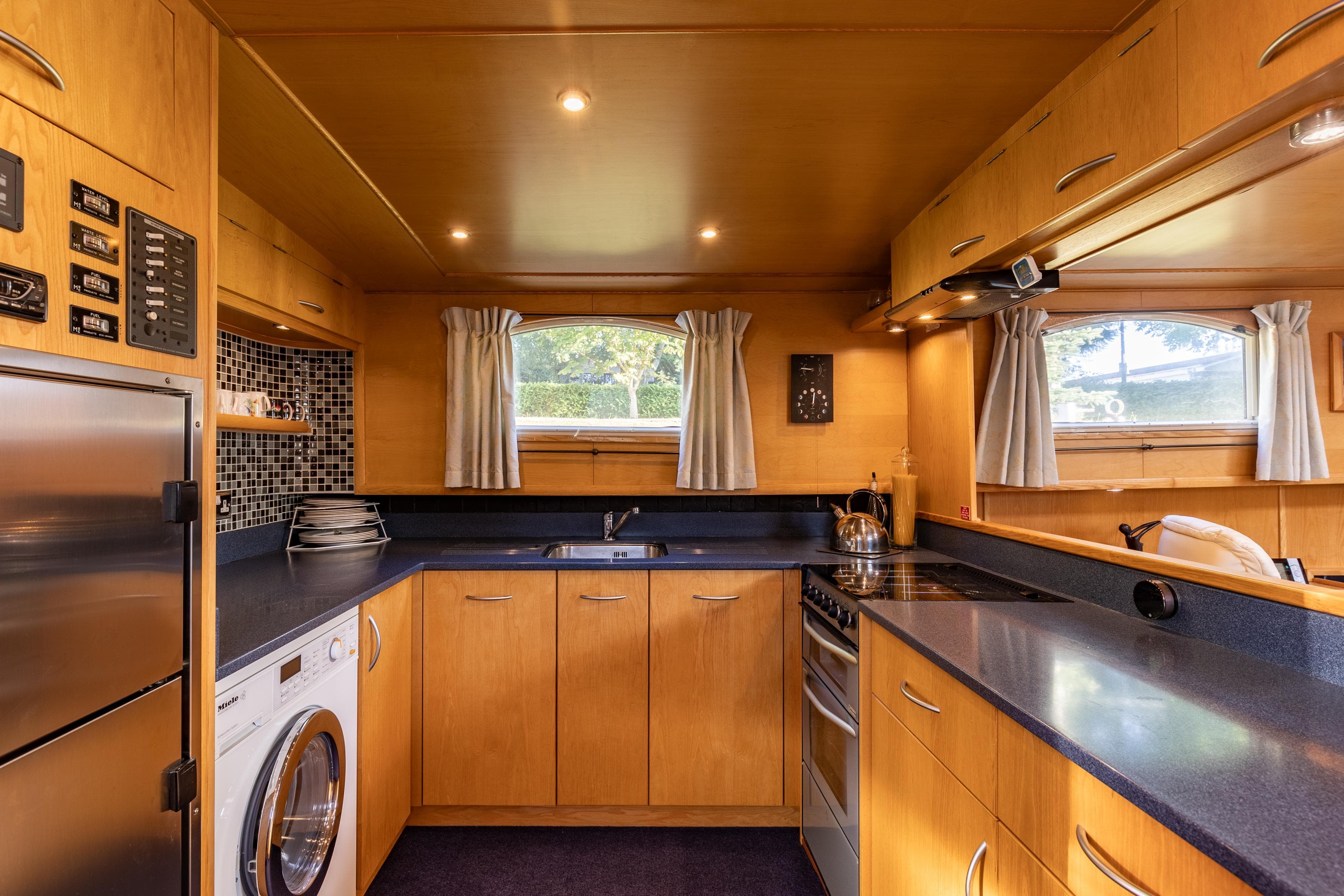 Modern kitchen interior in a 2009 Piper 55 boat, featuring wood cabinetry and stainless steel appliances.
