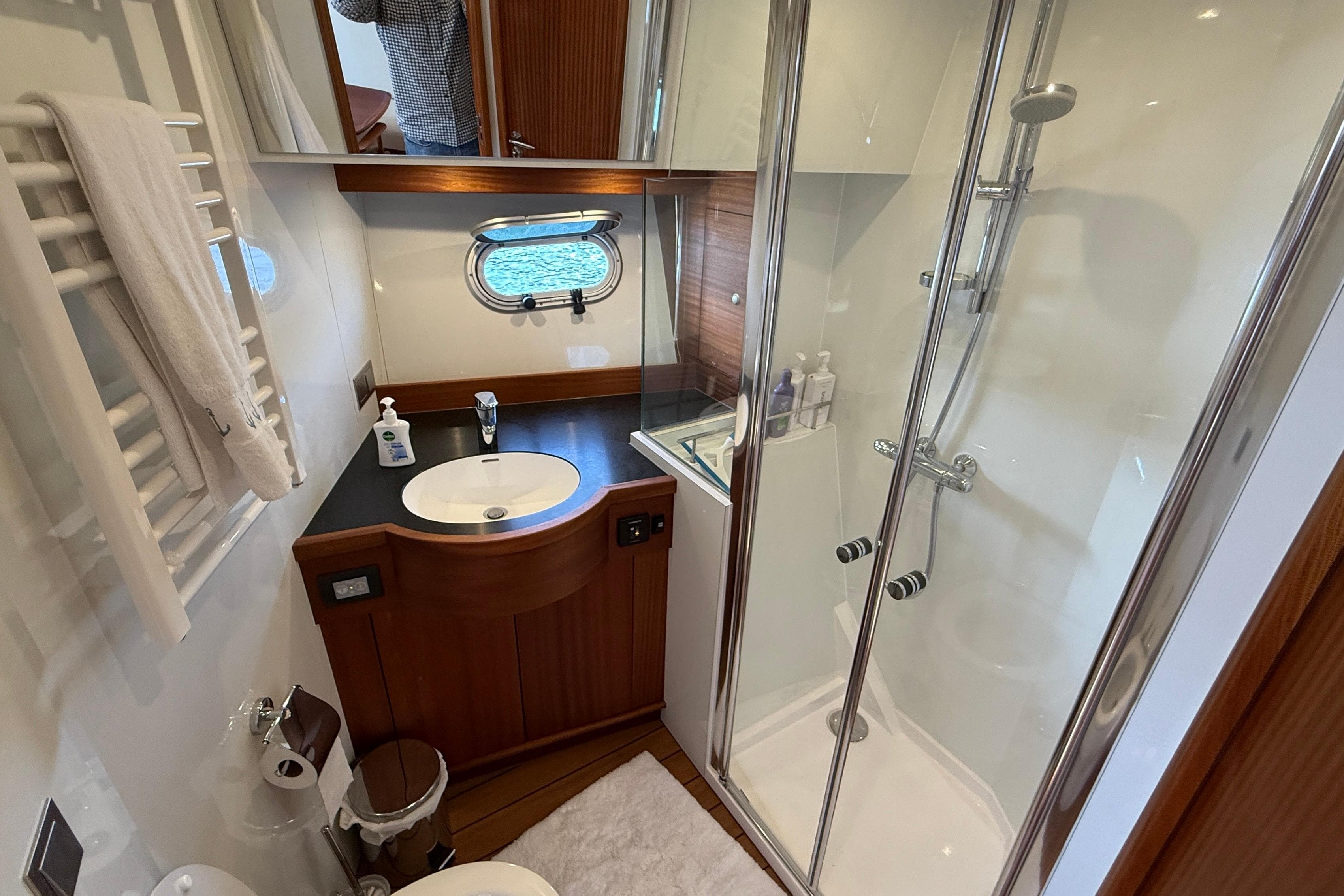 Luxurious bathroom in 2021 Elling E6 yacht with shower, sink, and porthole window.