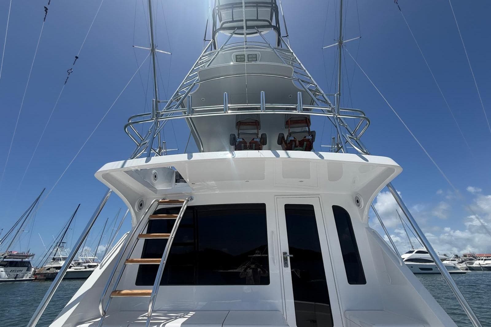 2003 Hatteras 54 Convertible yacht with tower, docked under clear blue sky.