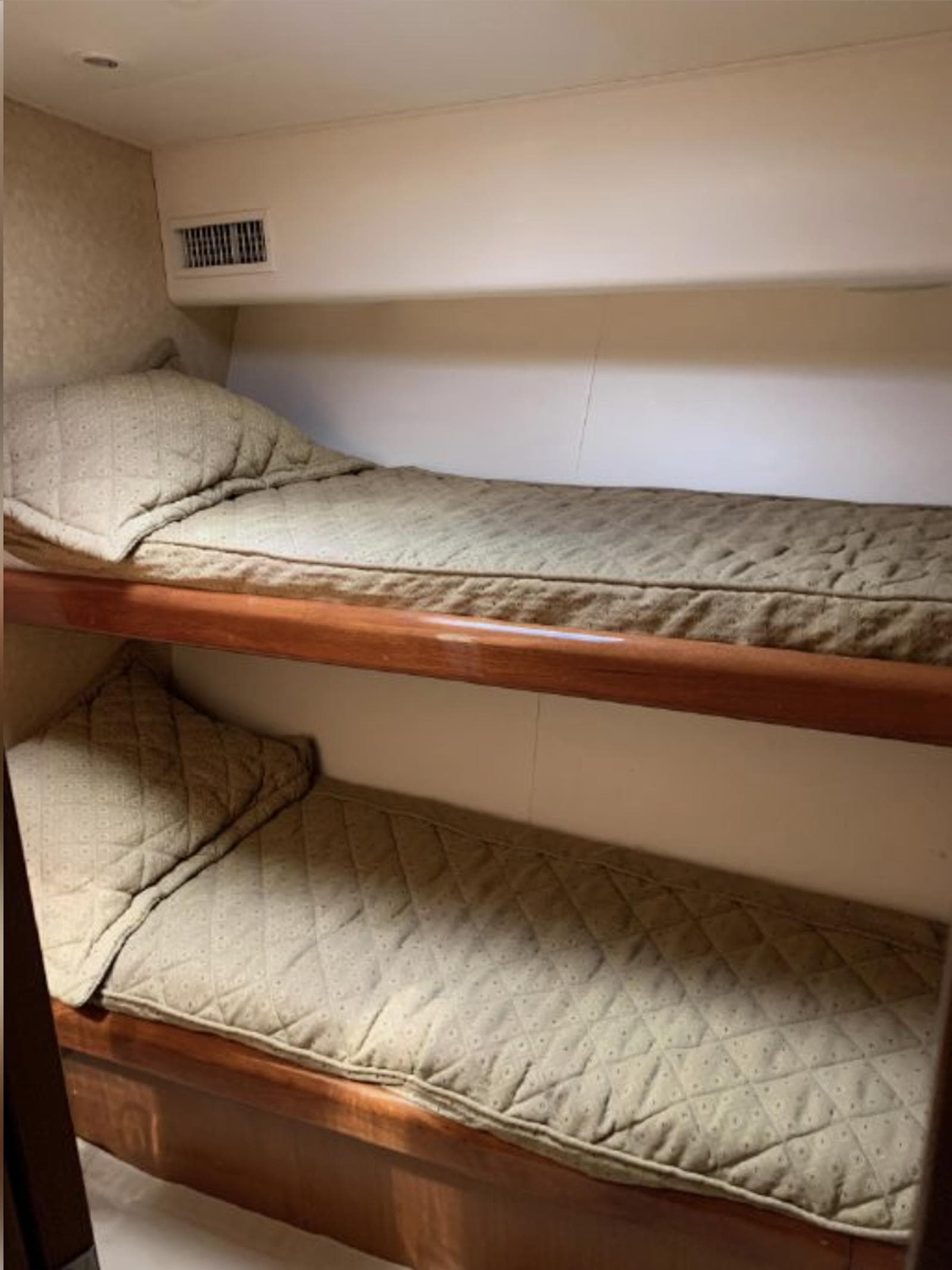 Bunk beds in 2000 Viking 55 Convertible yacht cabin, featuring wooden frames and beige bedding.