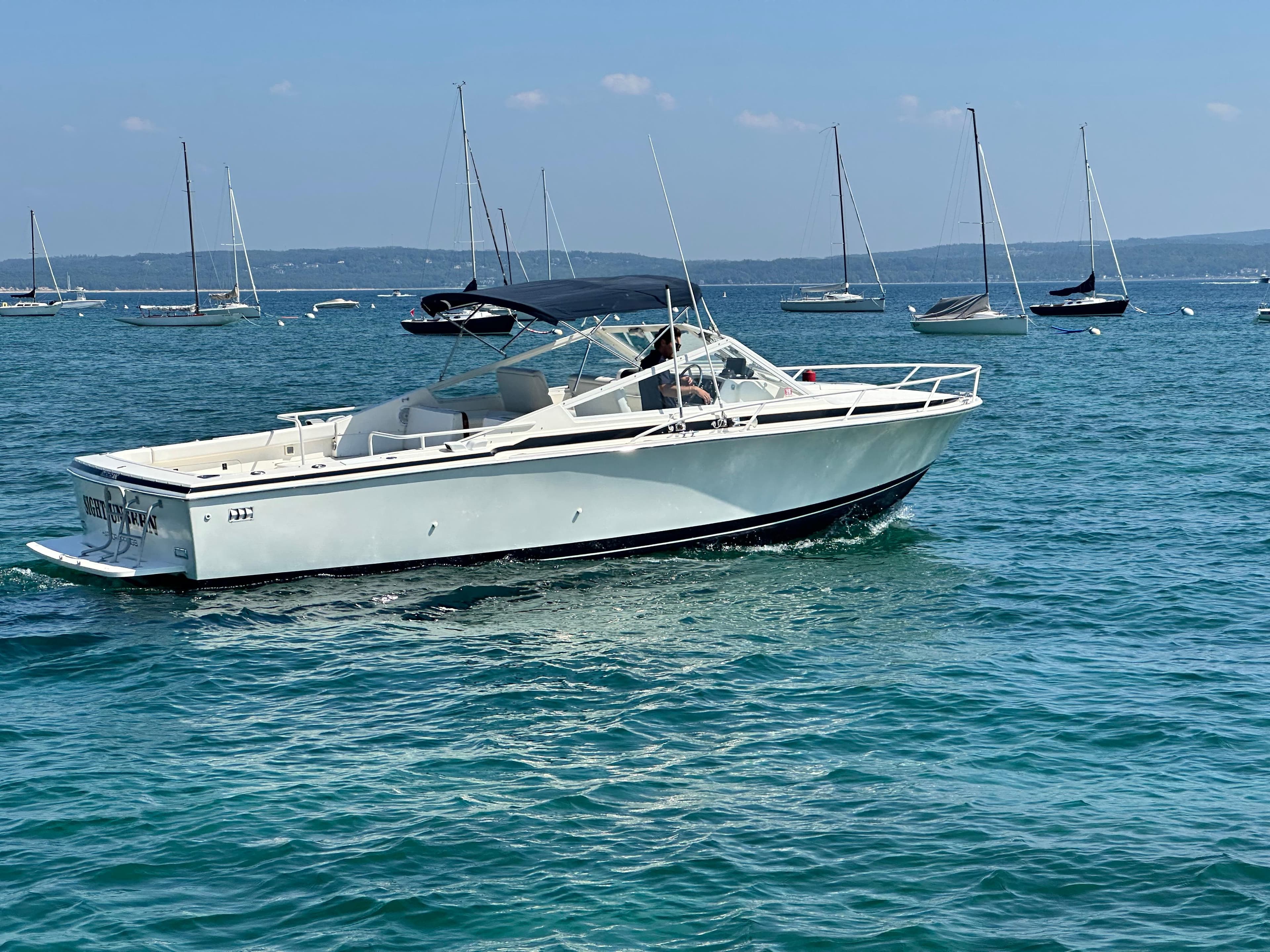 1988 Bertram 28 Moppie boat cruising on a sunny day with sailboats in the background.
