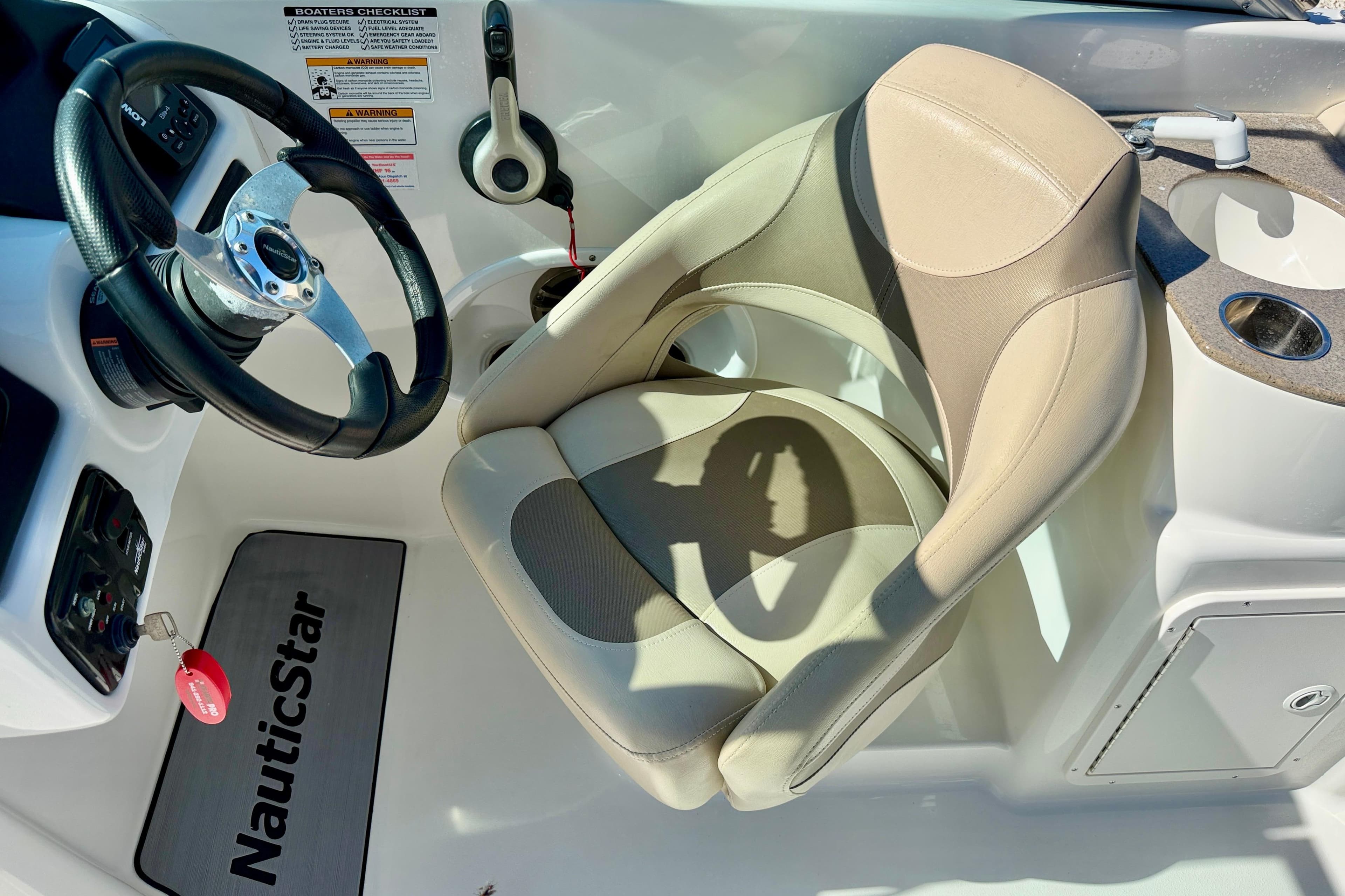 2014 NauticStar 243DC Sport Deck boat interior with steering wheel and captain's chair.