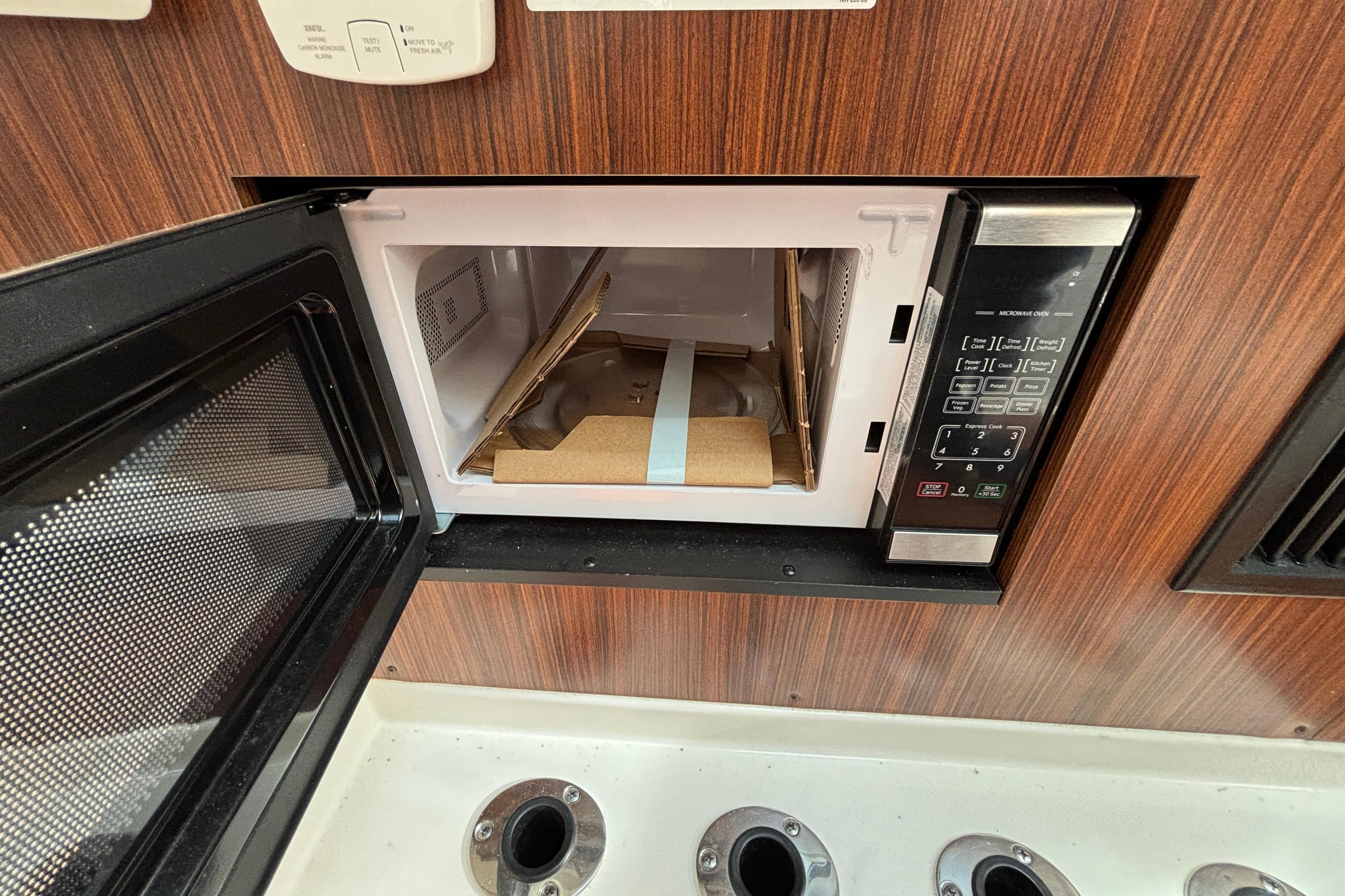 Microwave in 2022 Pursuit DC 365 Dual Console boat, open with packaging inside.