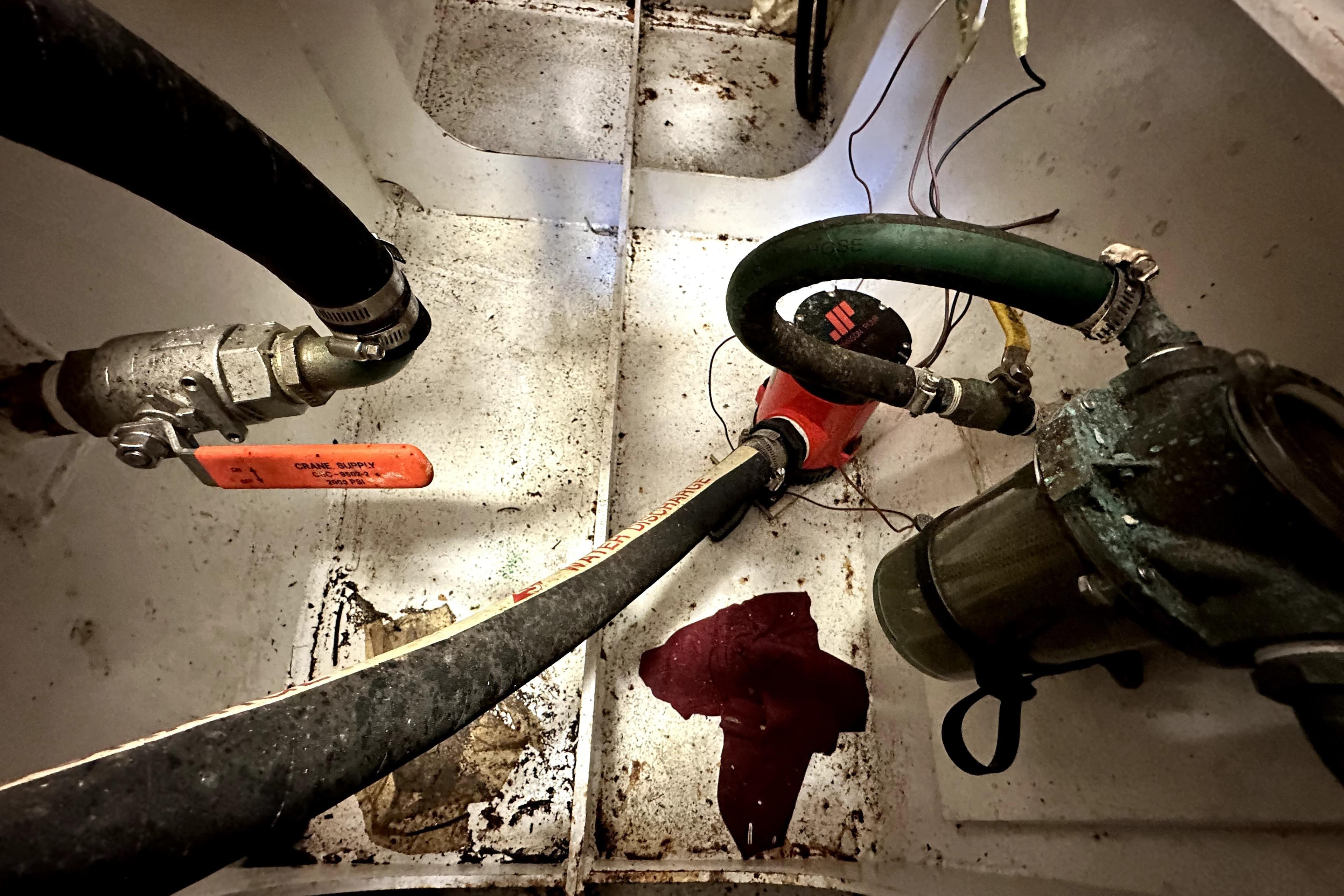 Bilge area of a 2012 Custom Pacific Northwest 43 boat with hoses and pump.