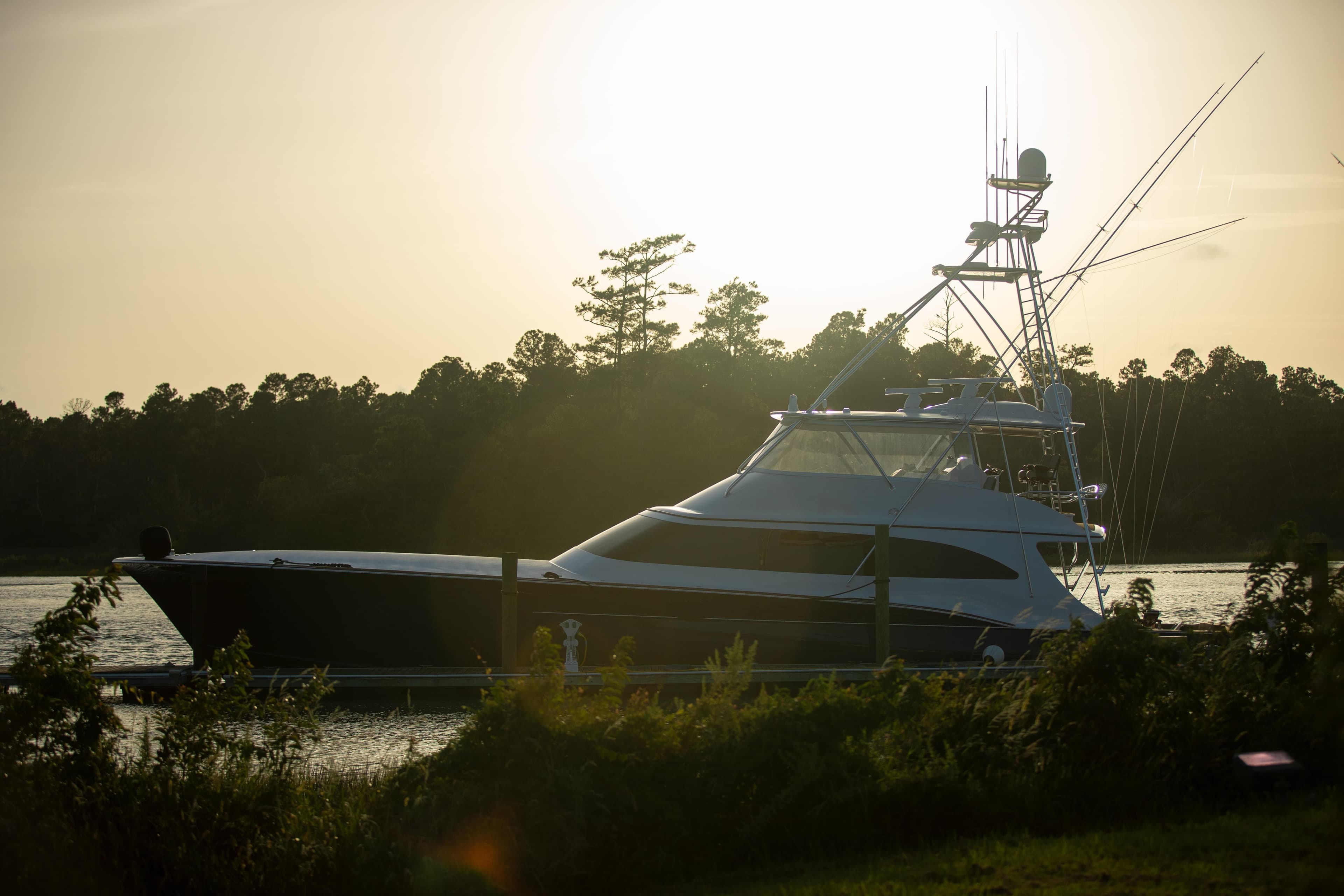 2020 Jarrett Bay 84 yacht docked at sunset, surrounded by lush greenery.