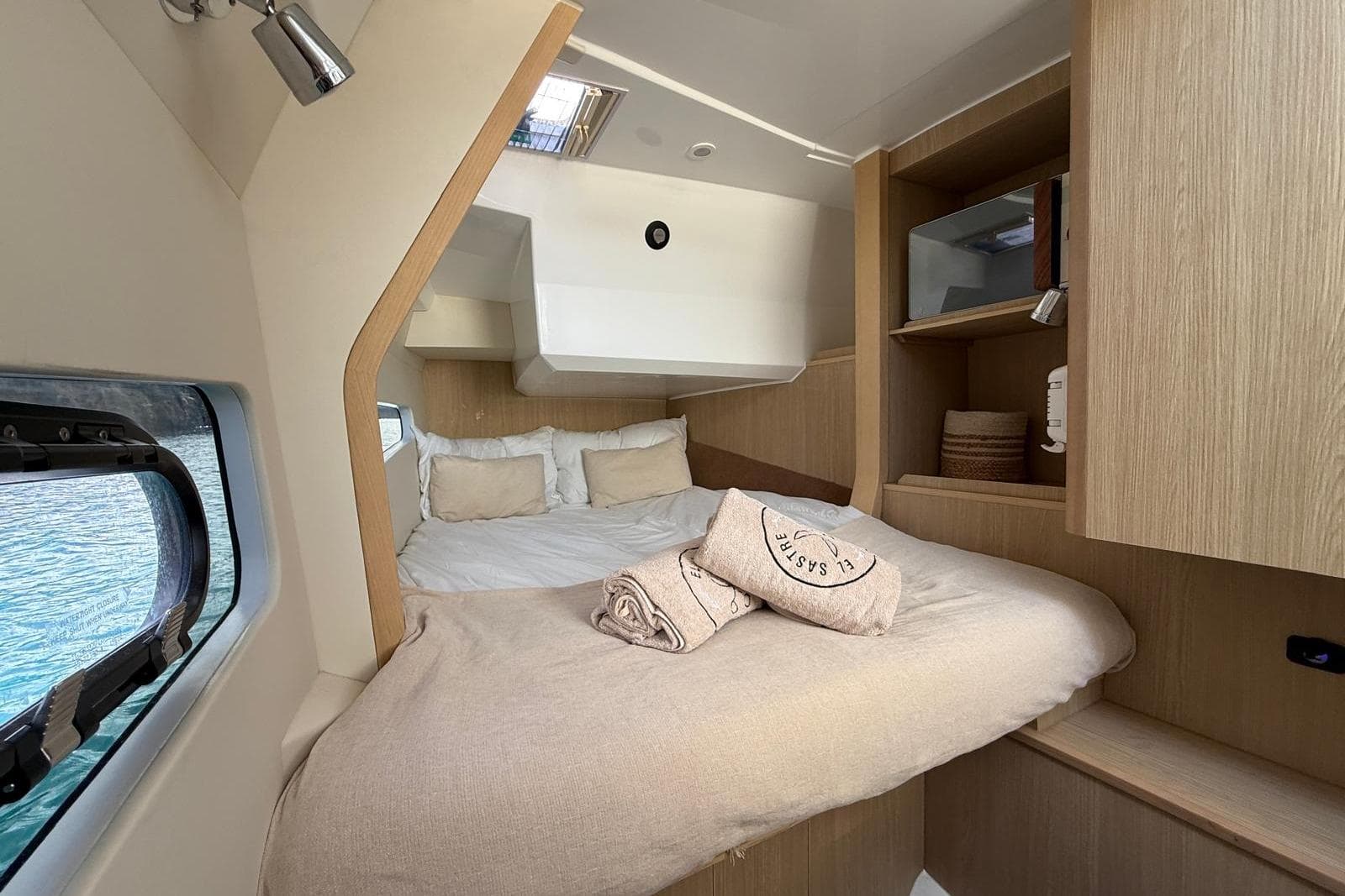 Luxurious cabin interior of 2023 Aquila 32 yacht with cozy bedding and wooden accents.