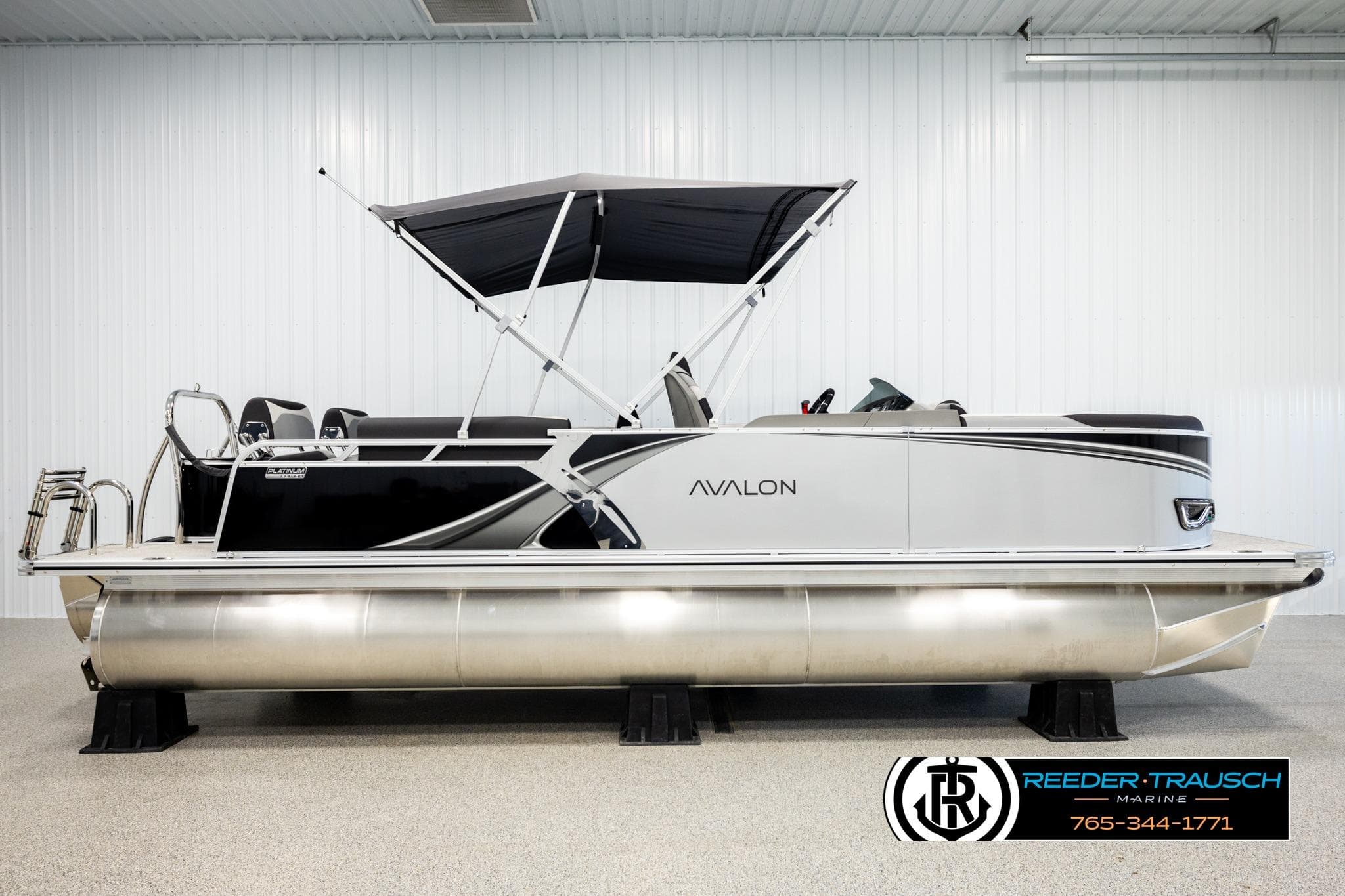 2026 Avalon LSZ QLS pontoon boat with canopy in showroom, Reeder-Trausch Marine logo visible.