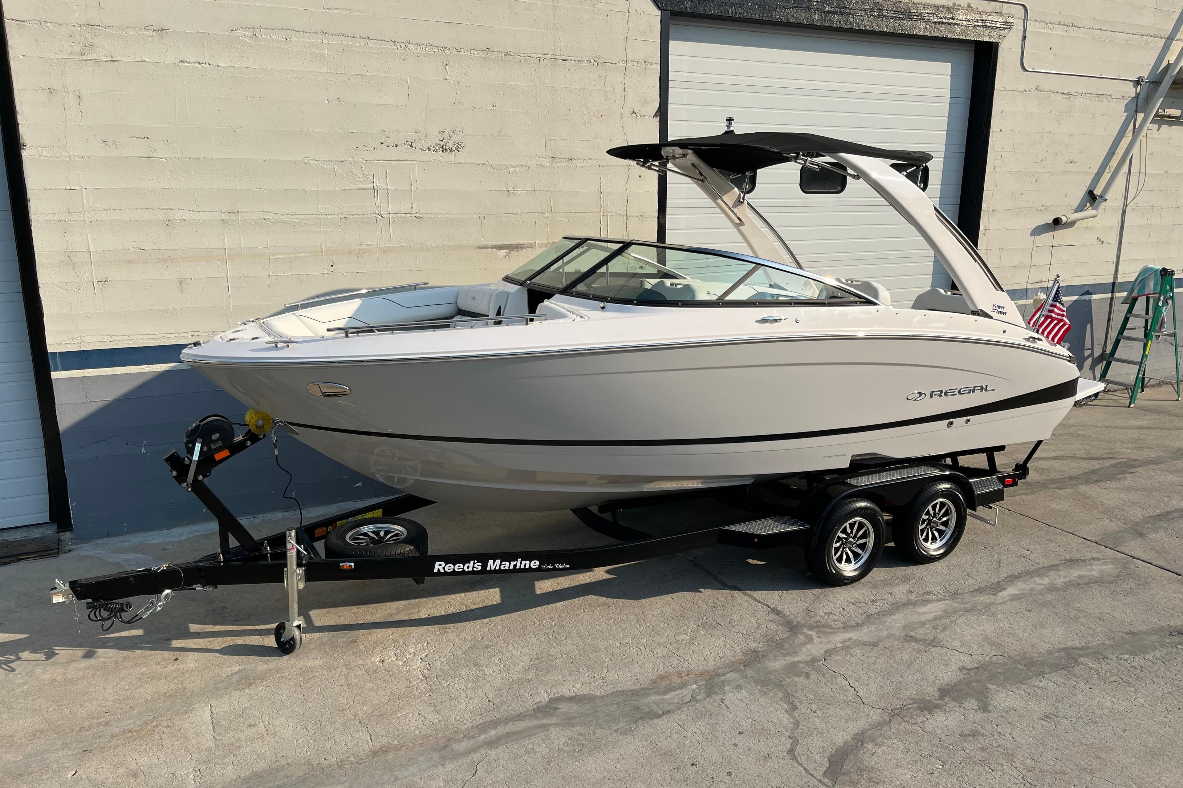 2025 Regal LS4 boat on trailer, parked outside a garage.