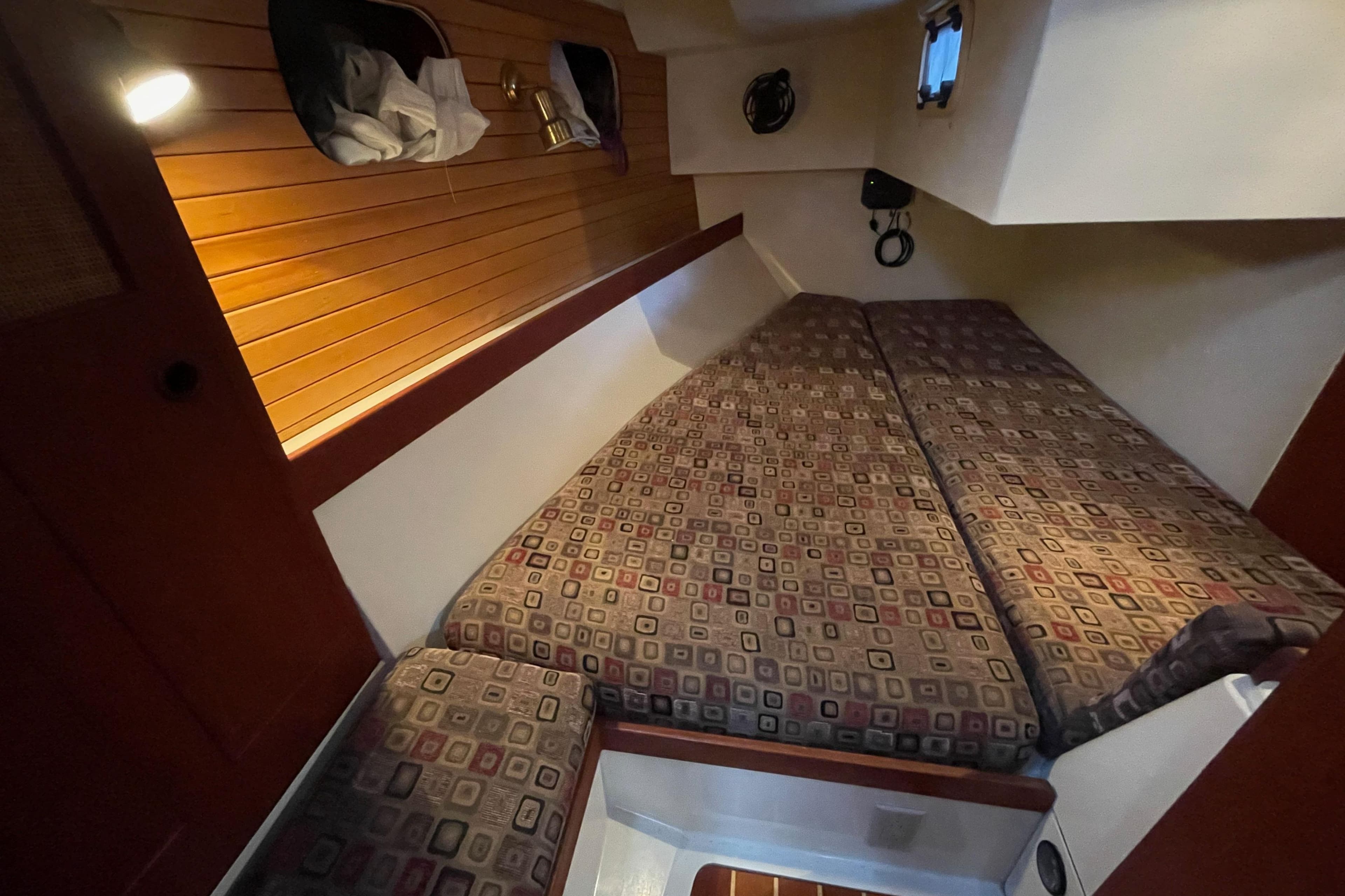 Cozy cabin interior of 1988 CS 36 Merlin sailboat with patterned cushions and wood paneling.