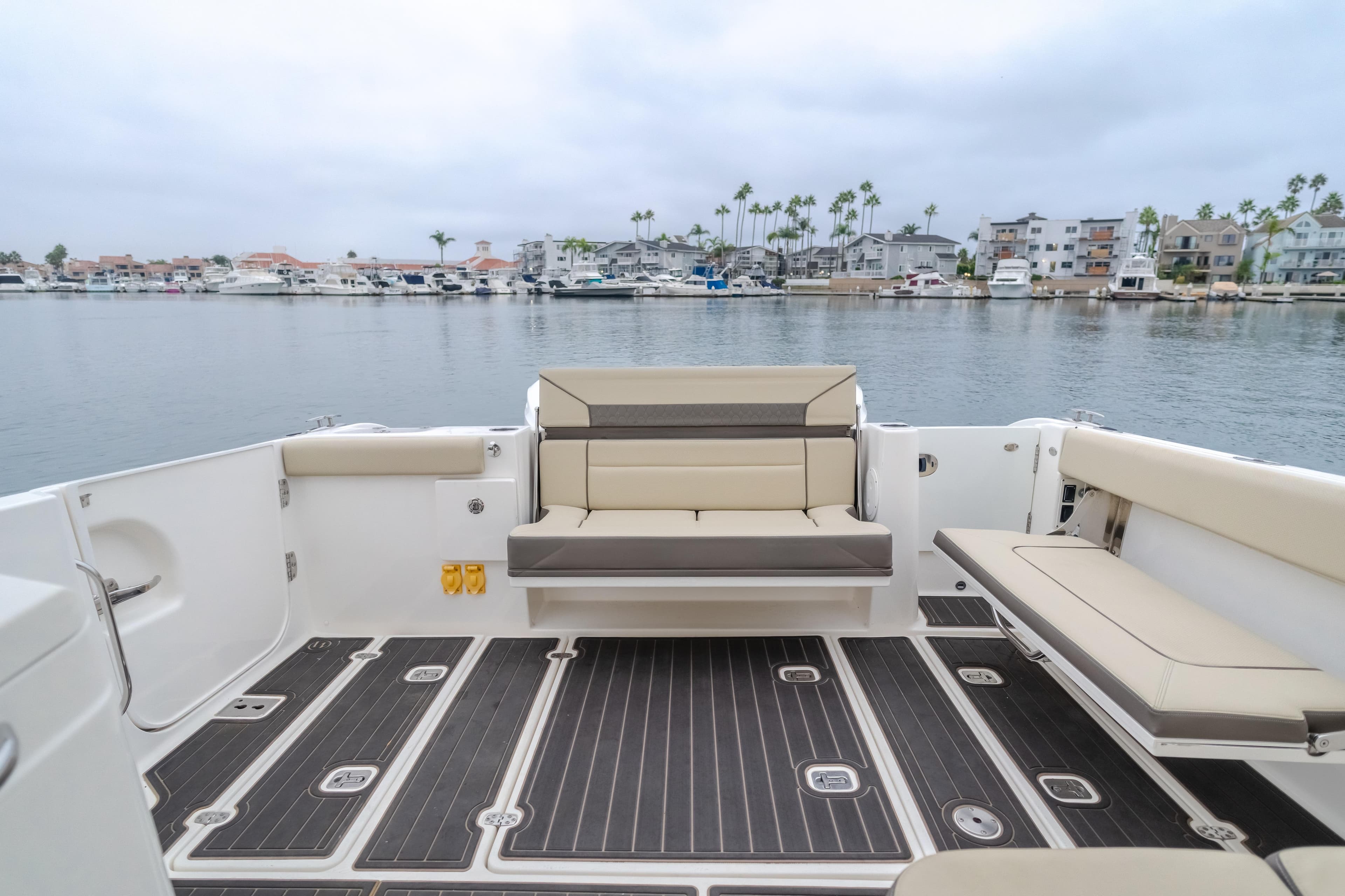 2018 Pursuit boat interior with beige seating, overlooking marina and waterfront homes.