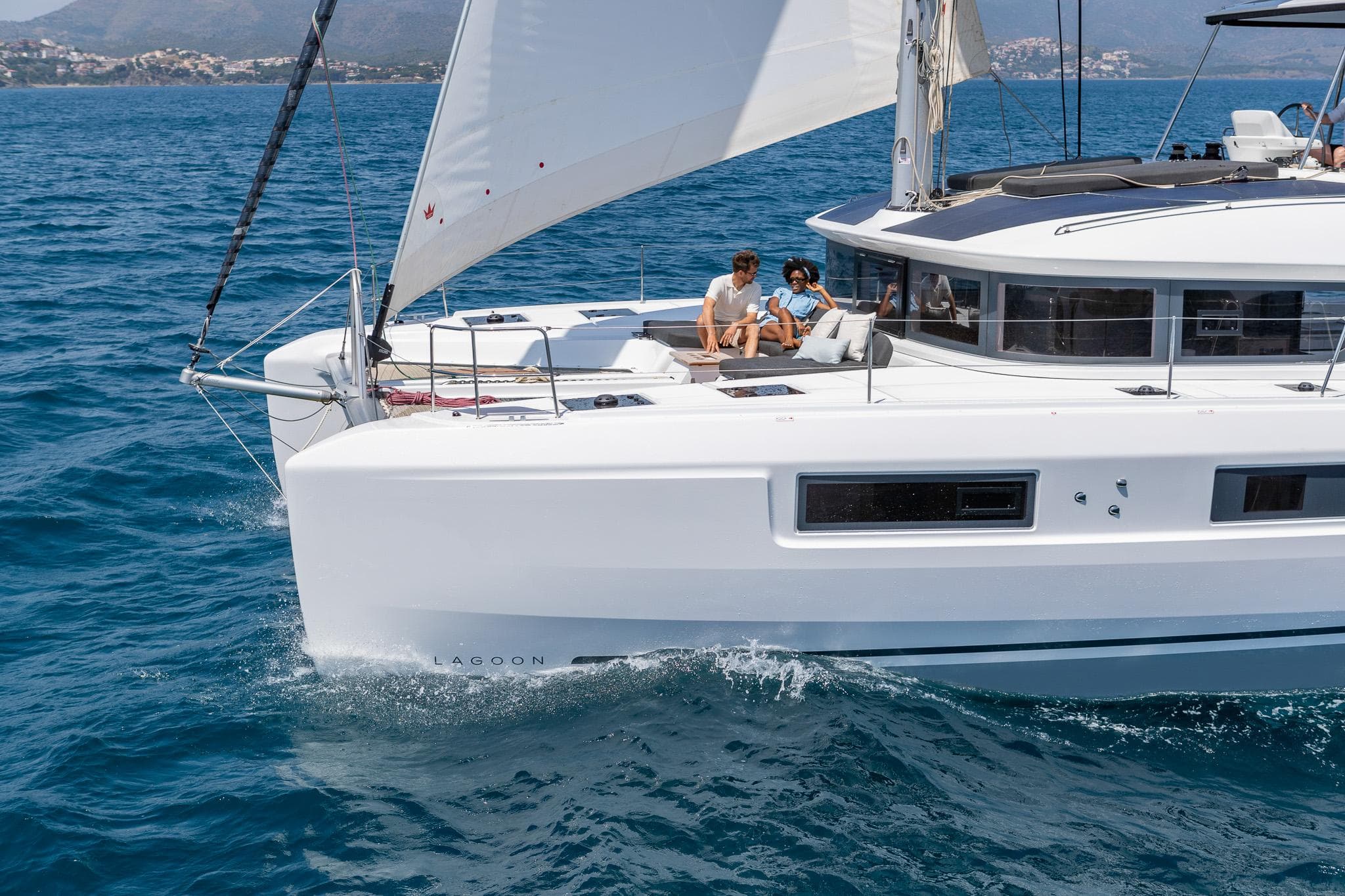 2025 Lagoon 51 ICONIC sailing on blue ocean with passengers enjoying the view.