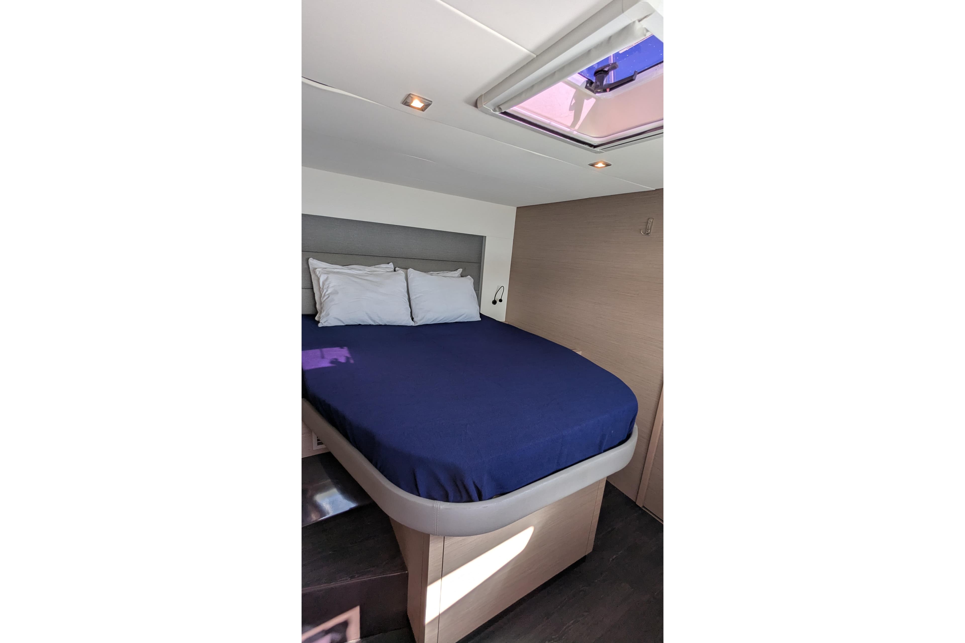 2020 Fountaine Pajot Saona 47 cabin with blue bedding and overhead skylight.