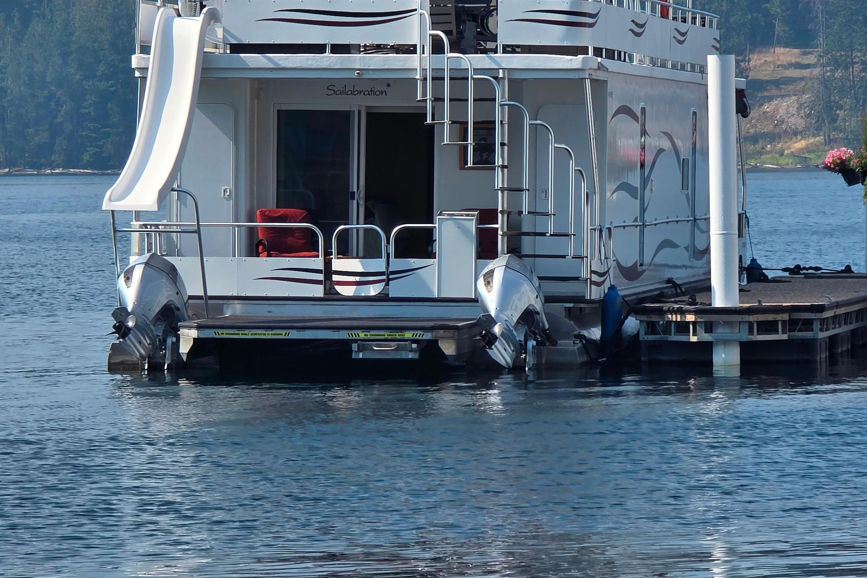 Houseboat with slide, Sailabration 64, 2015 model, docked on a serene lake.