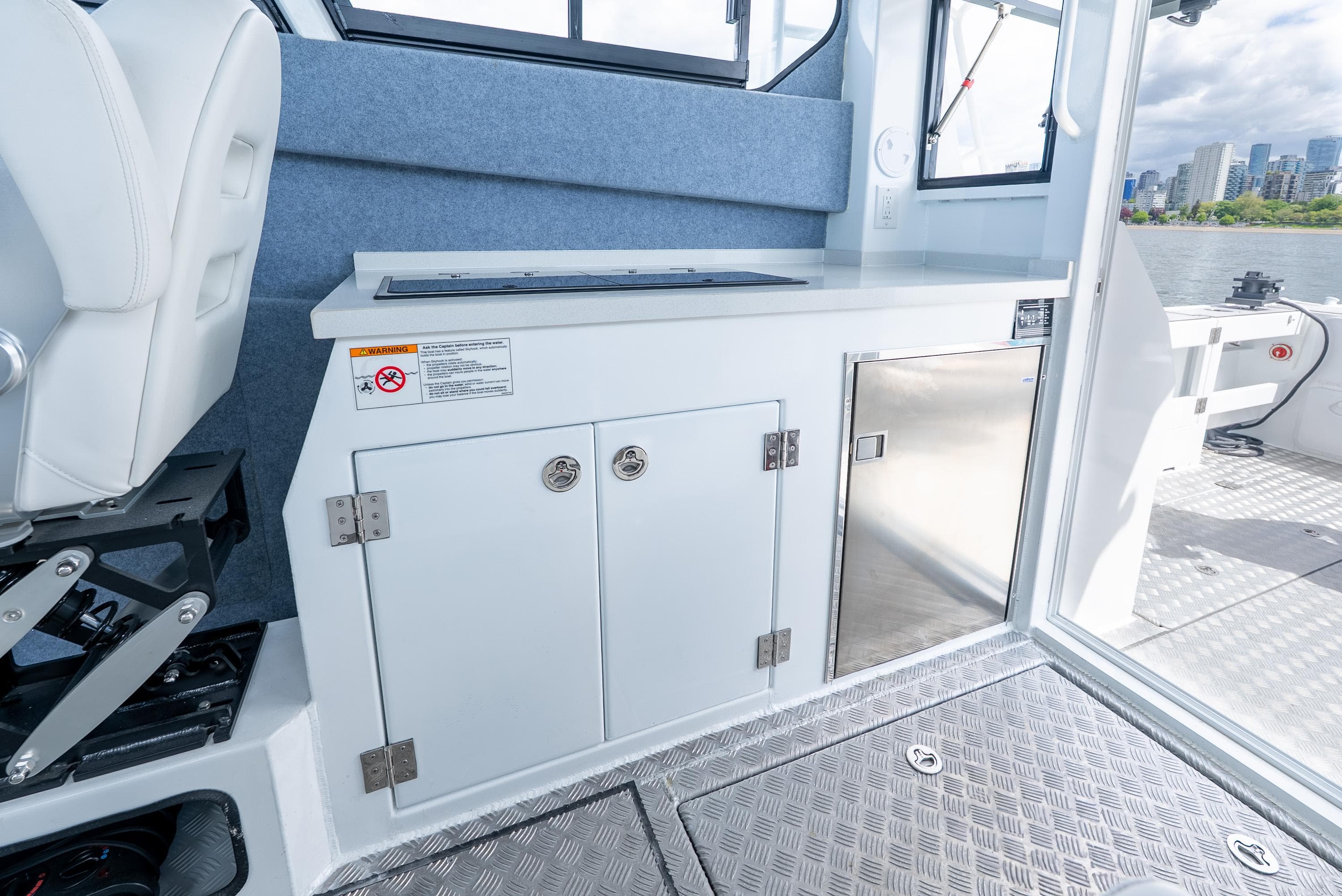Interior of 2025 Custom Ocean Craft 1106 boat, featuring storage cabinets and stainless steel surfaces.