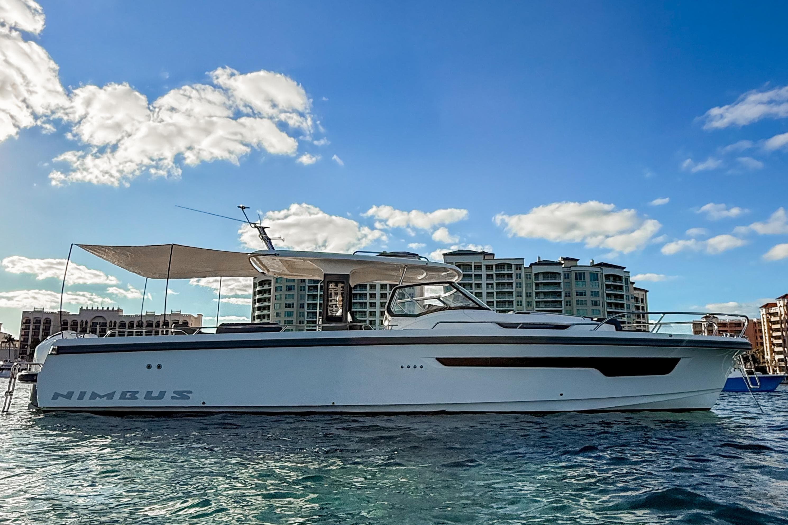 2022 Nimbus T11 yacht on water, cityscape background, clear sky.