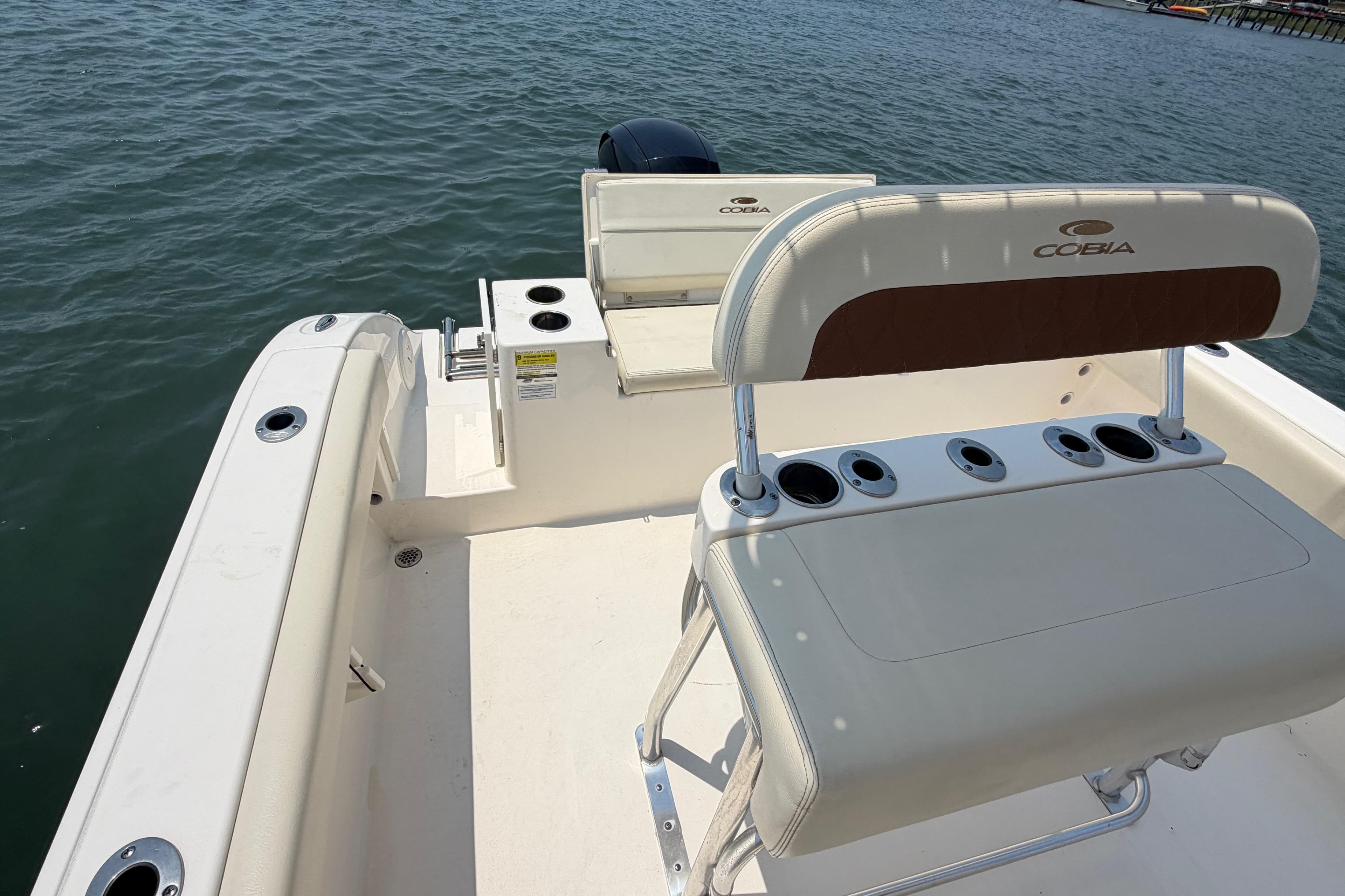 2023 Cobia 220 Center Console boat interior with seating and rod holders on the water.