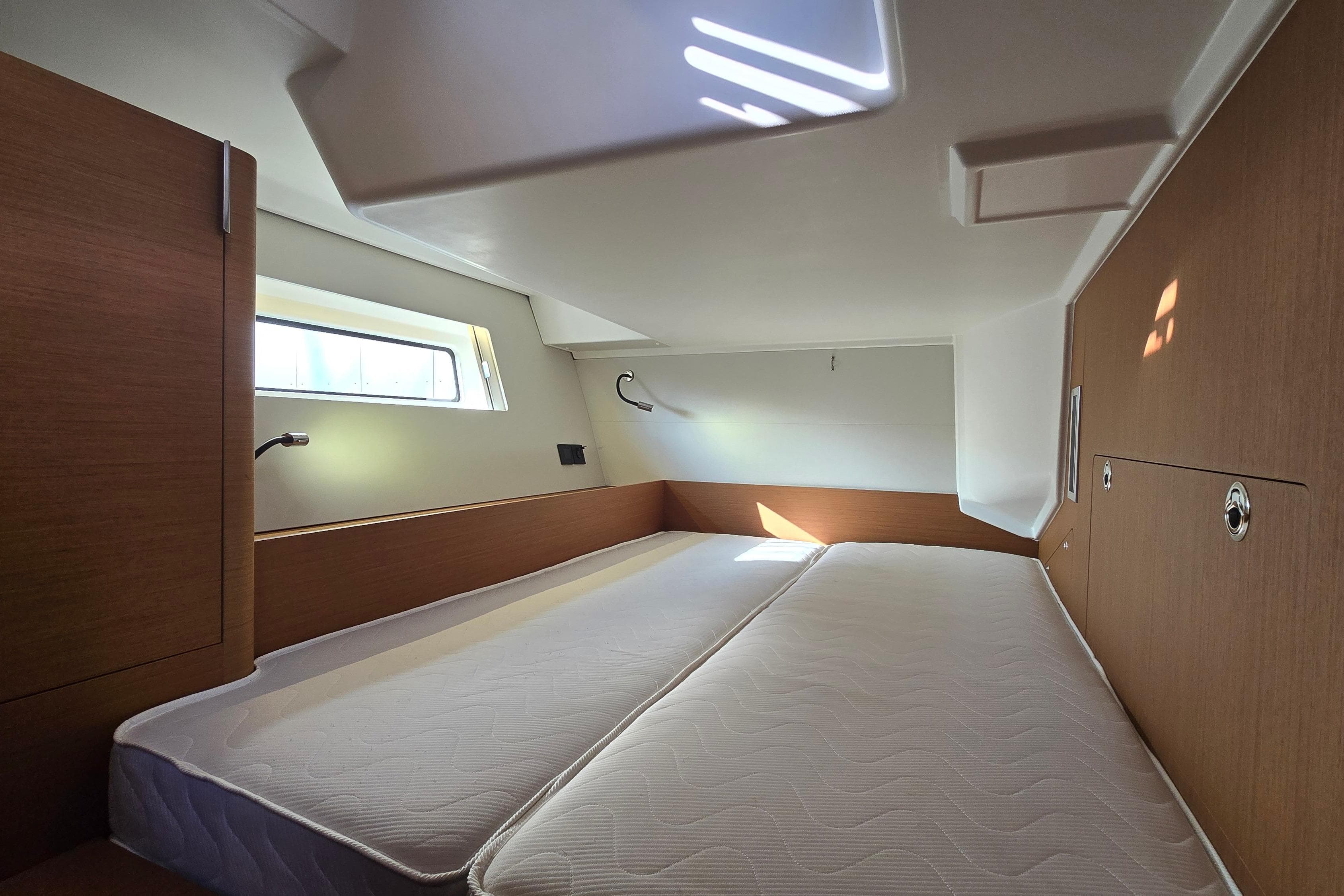 Luxurious cabin interior of 2022 Beneteau First 53 yacht, featuring modern design and comfortable bedding.