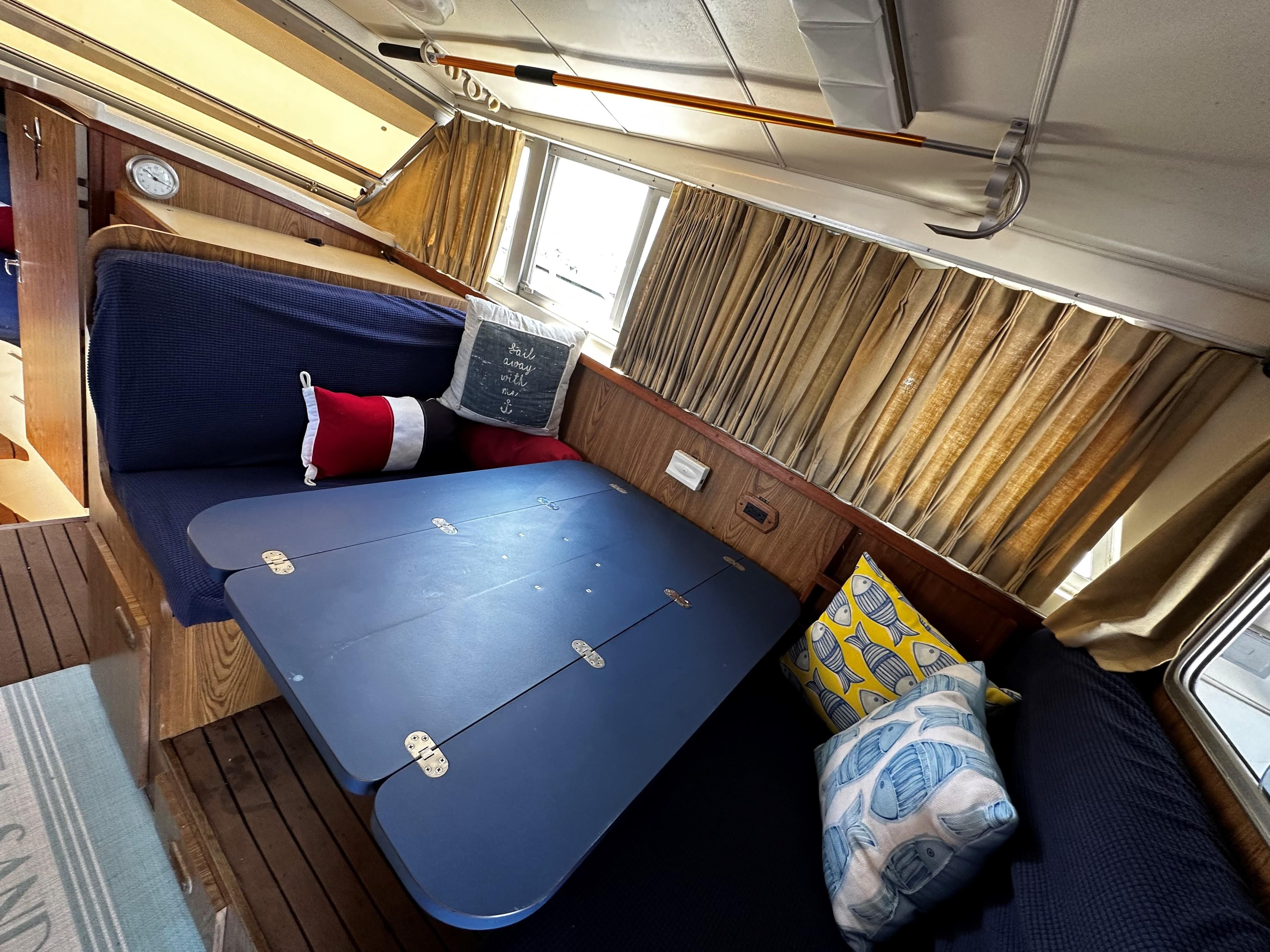 Interior of 1980 Bertram 33 Sport Fisherman with blue seating and foldable table.