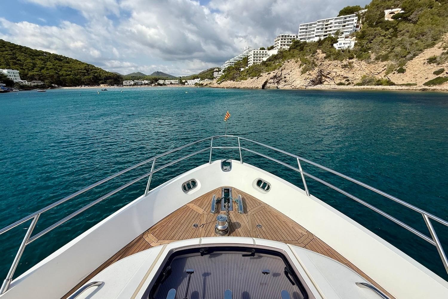 Bow view of 2015 Princess V72 yacht approaching scenic coastal landscape.