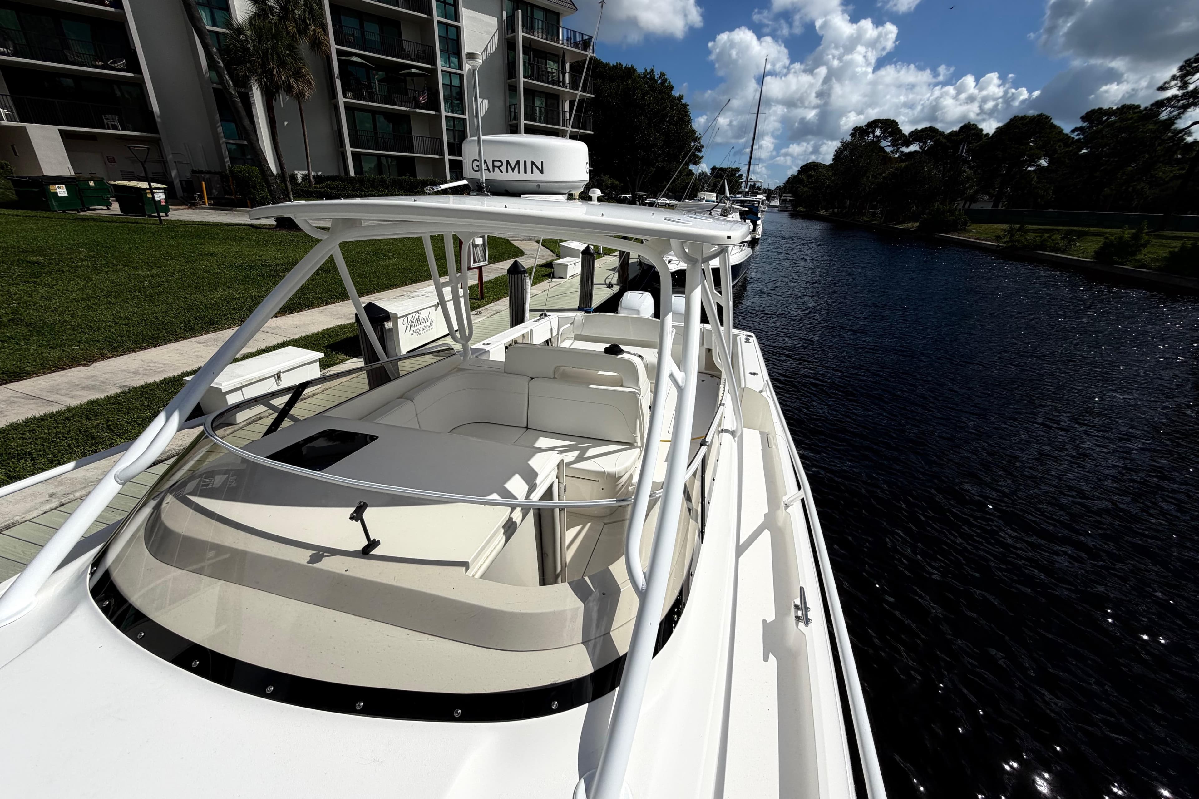 2008 Intrepid 350 Center Console boat docked by a canal under a sunny sky.