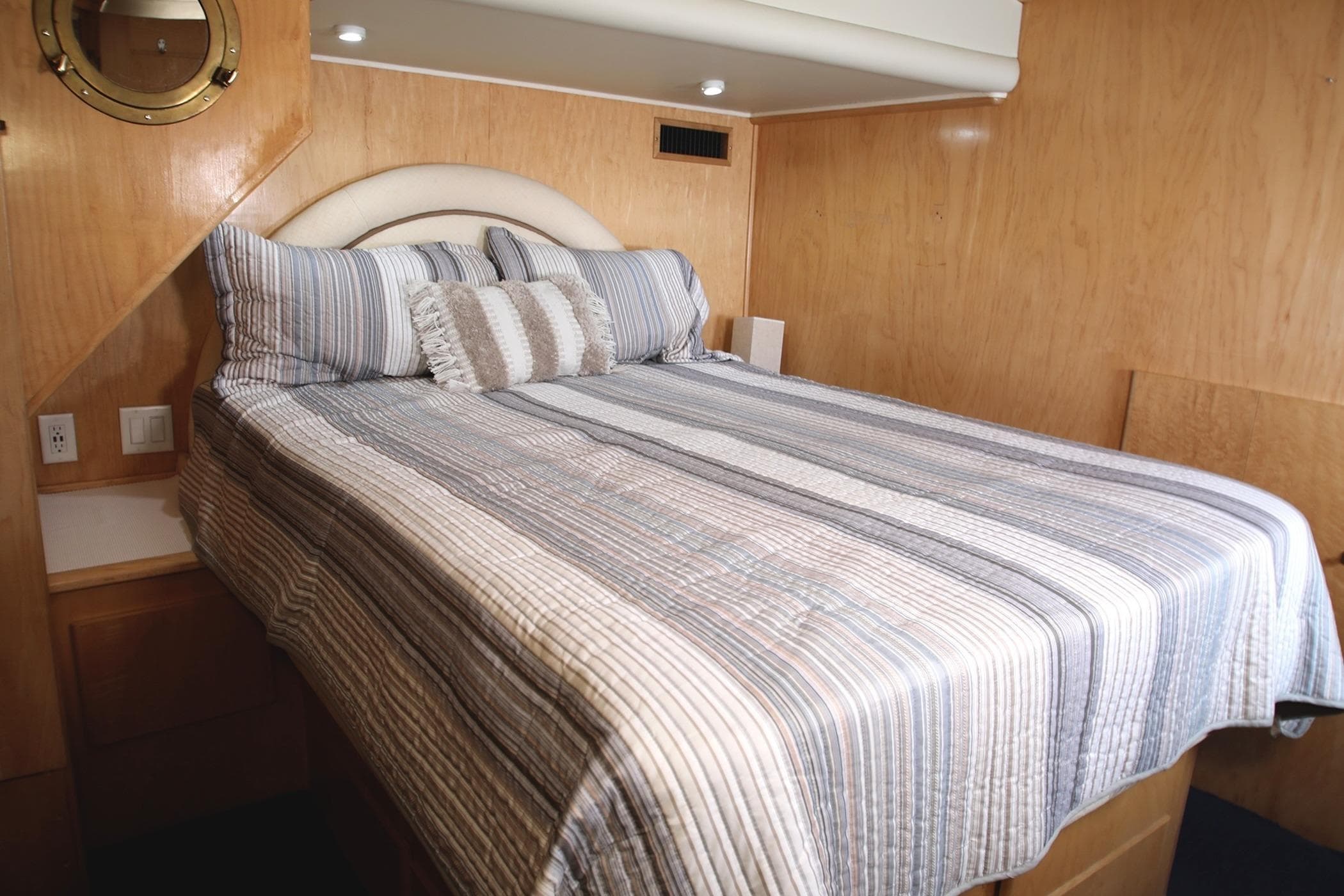 Cozy bedroom interior of 1996 Navigator Classic 50 yacht with striped bedding.