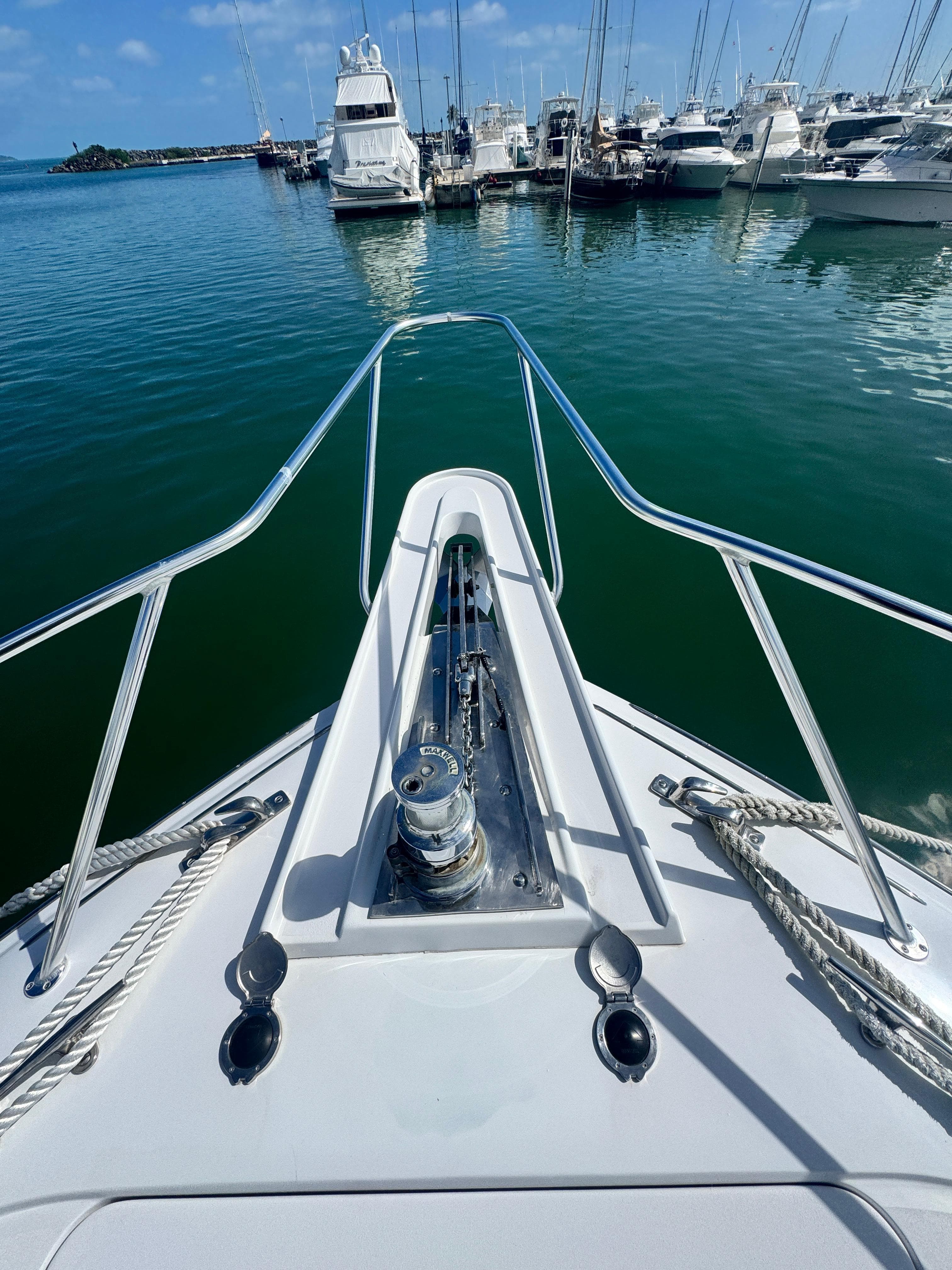 Bow view of 2011 Hatteras GT60 yacht docked in marina, surrounded by boats.