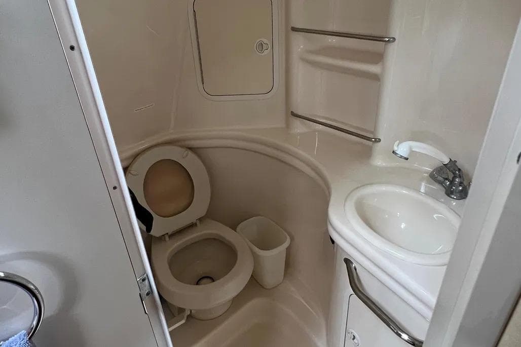 Compact bathroom in 2002 Sea Ray 300 Sundancer boat with toilet and sink.