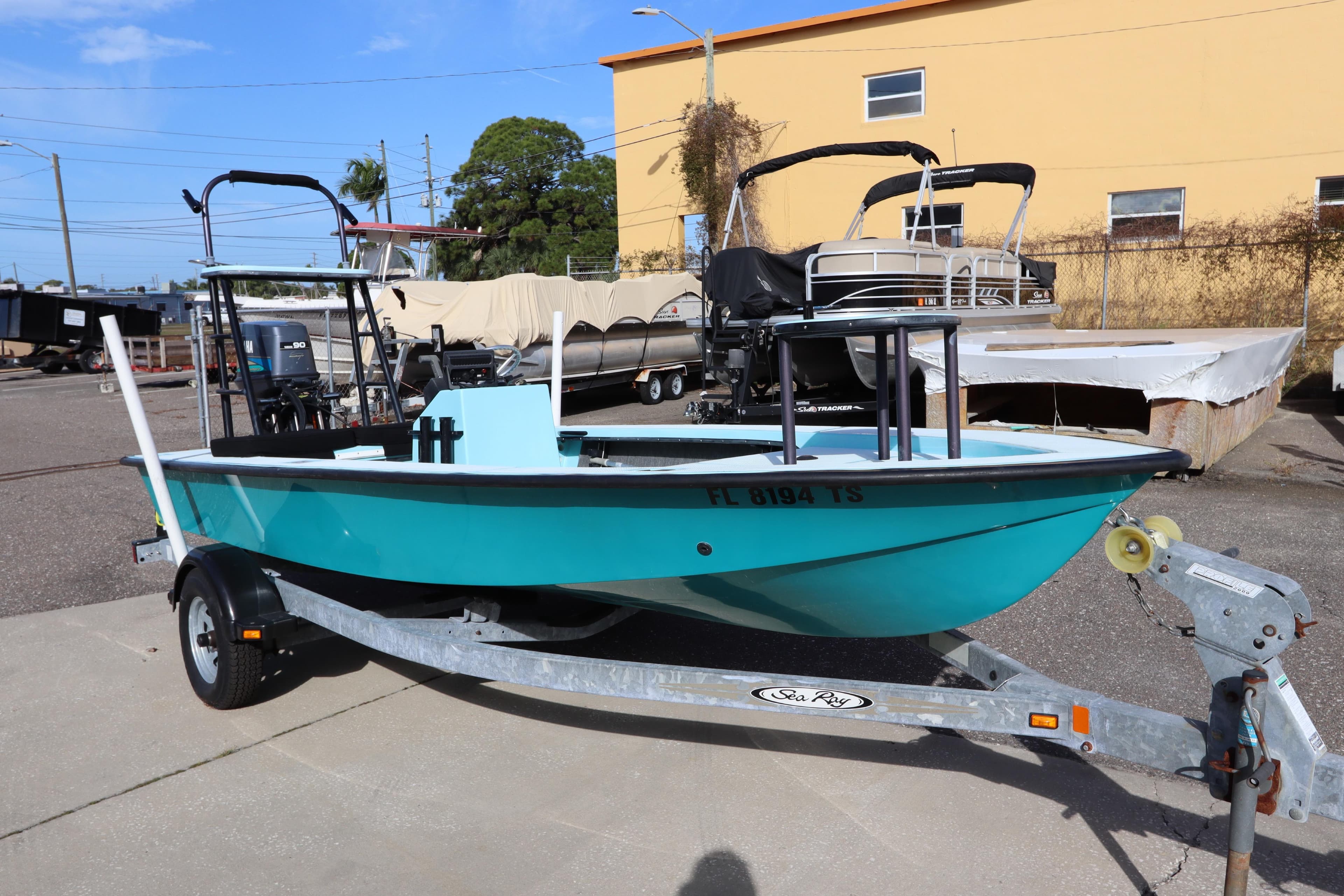 1996 Silver King Signature 16 boat on trailer, turquoise hull, parked outdoors.